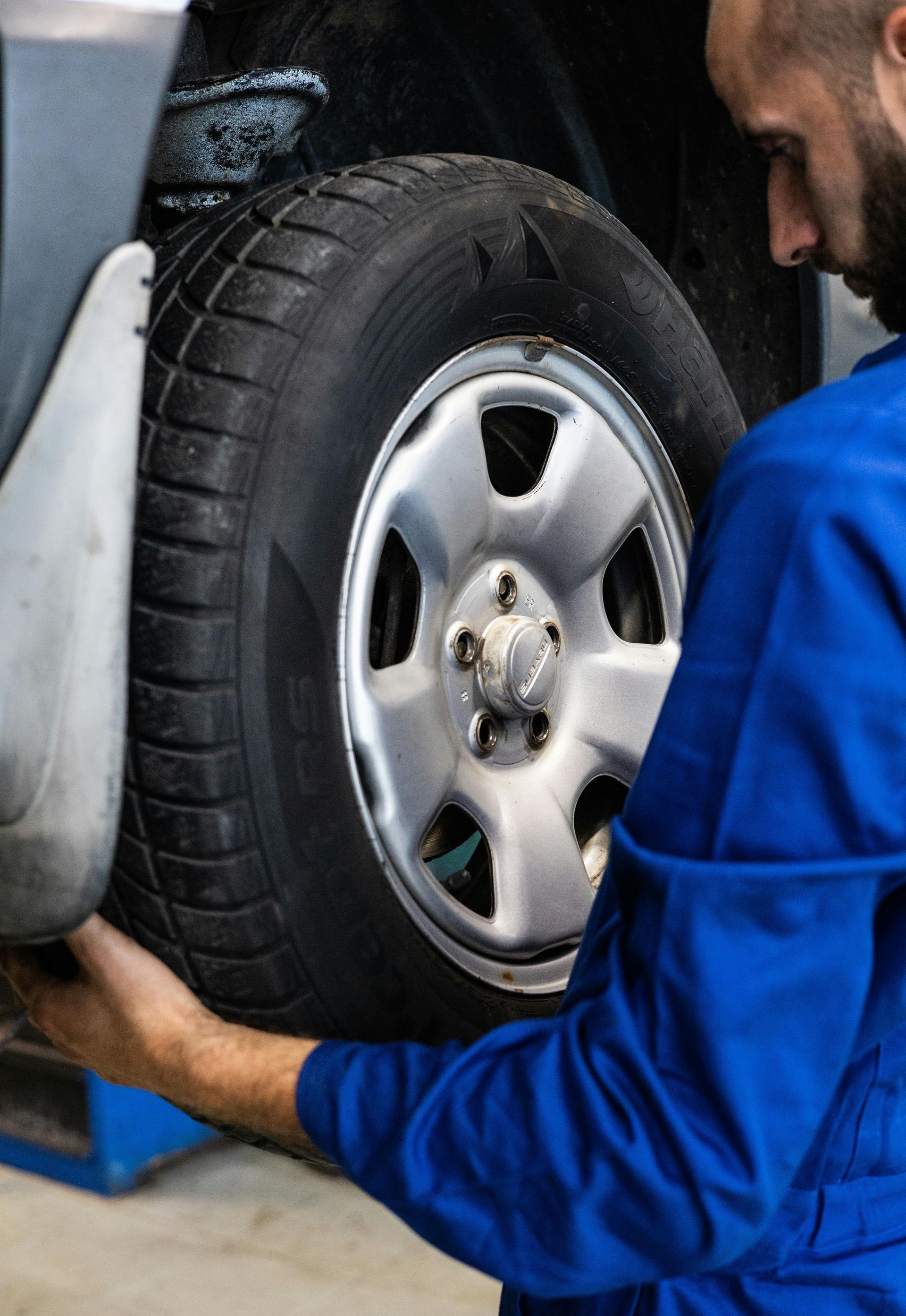 A man in a blue uniform is changing a tire on a car.