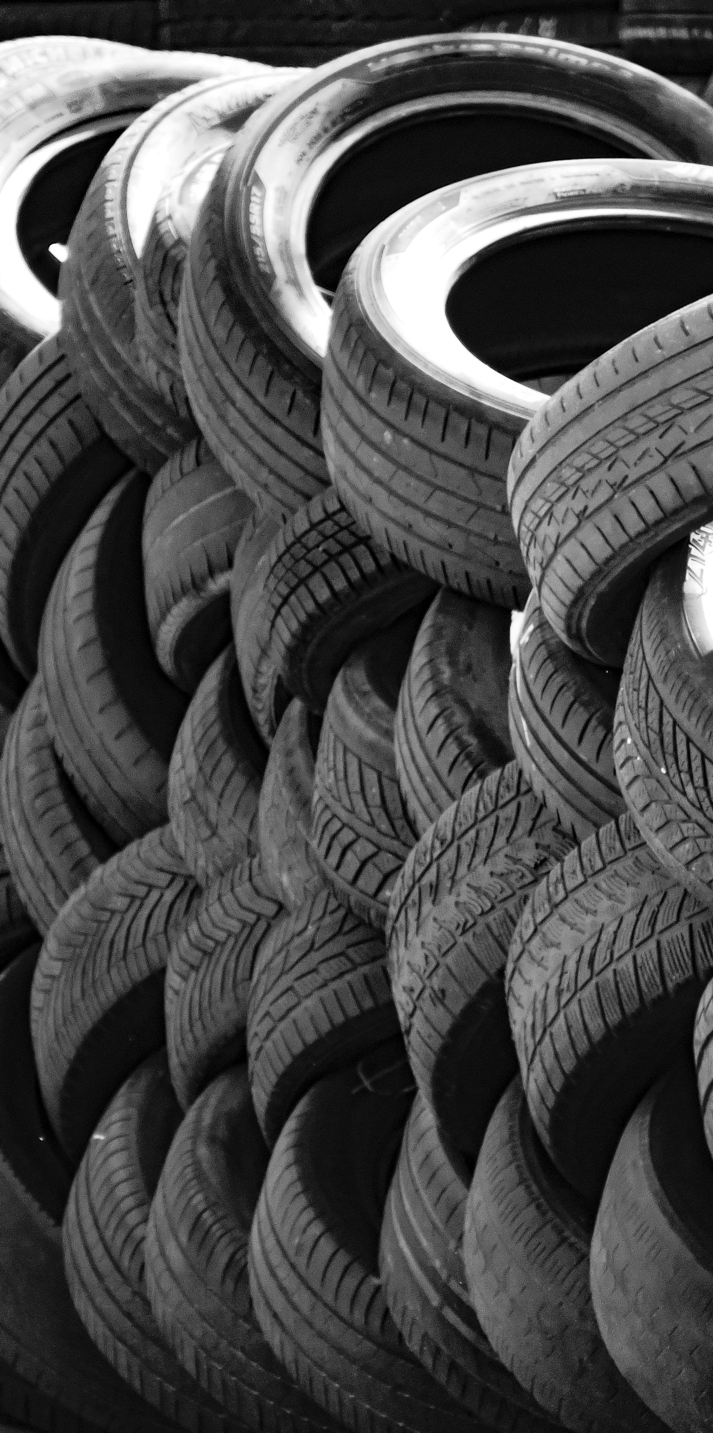 A black and white close-up of a stacked pile of used vehicle tires.