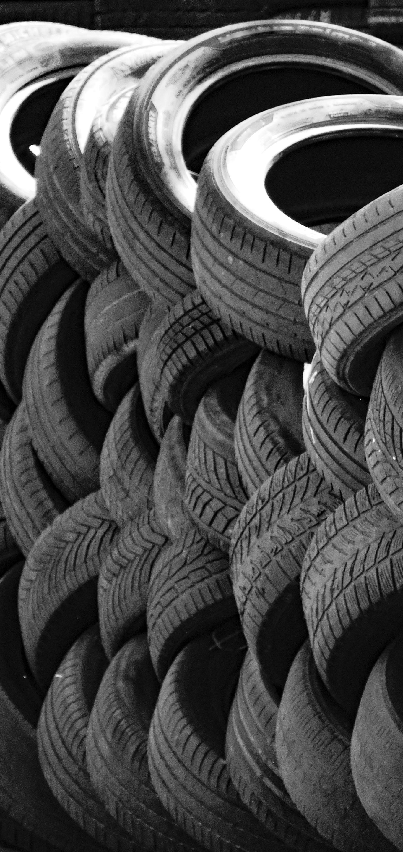 A black and white close-up of a stacked pile of used vehicle tires.