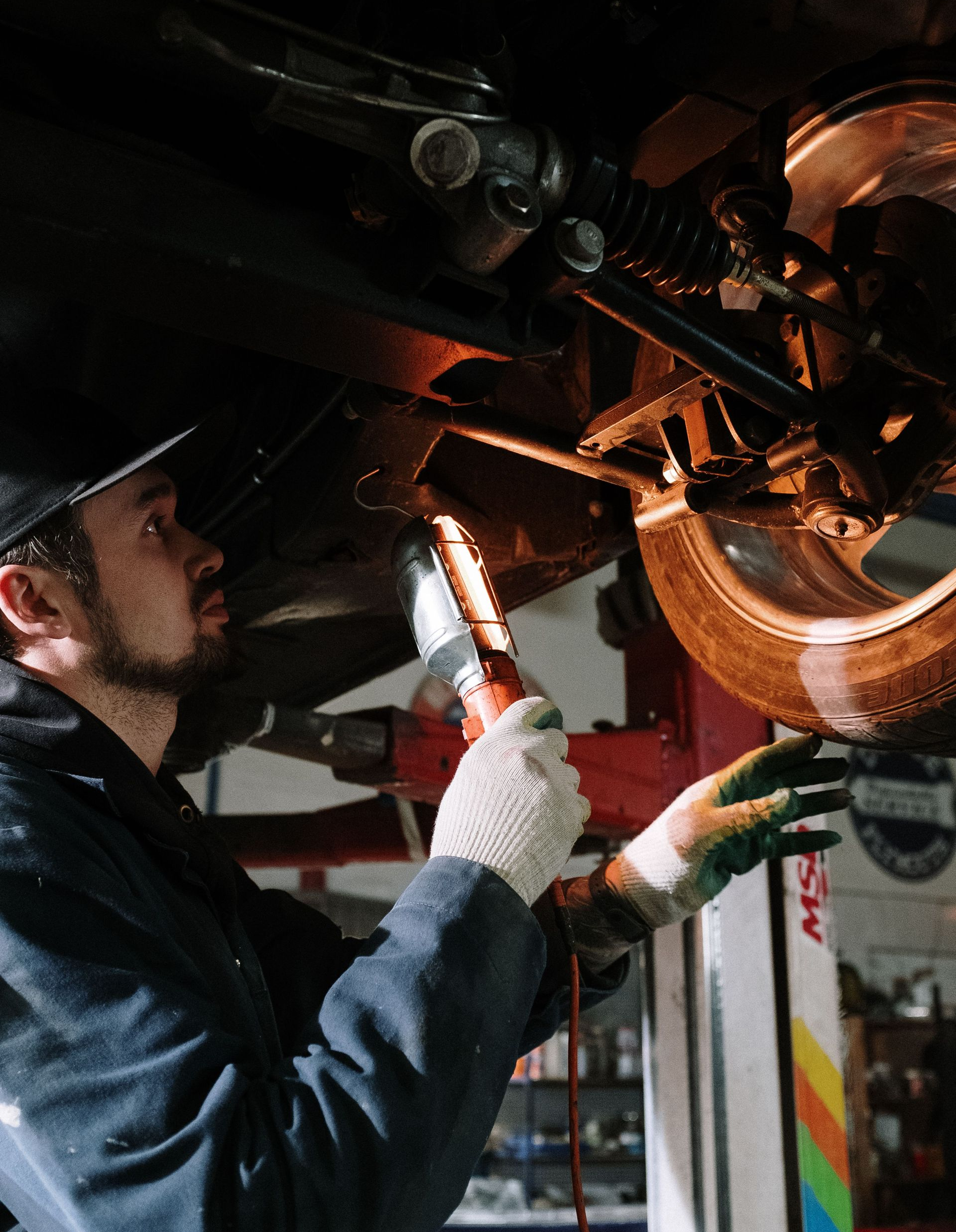 Mechanic inspecting motorcycle engine with a flashlight in a dim garage