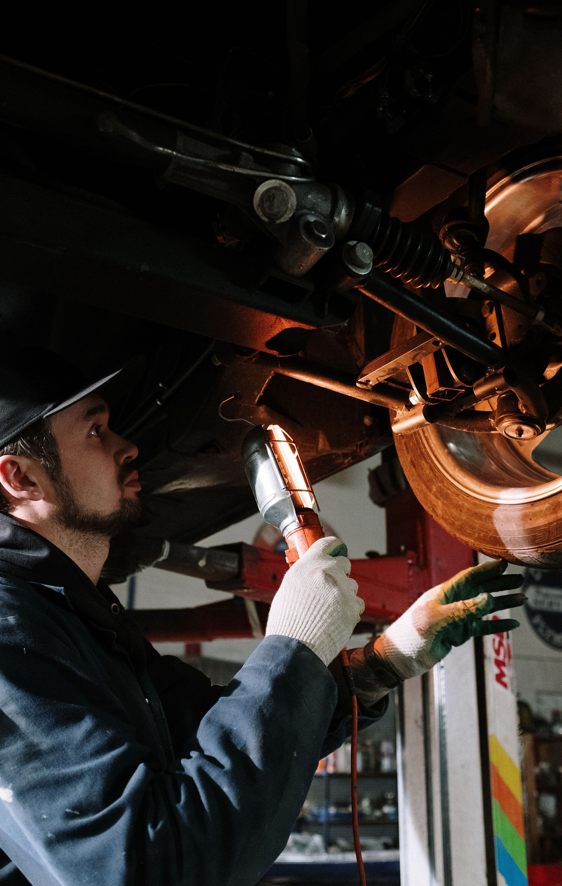 Mechanic inspecting motorcycle engine with a flashlight in a dim garage