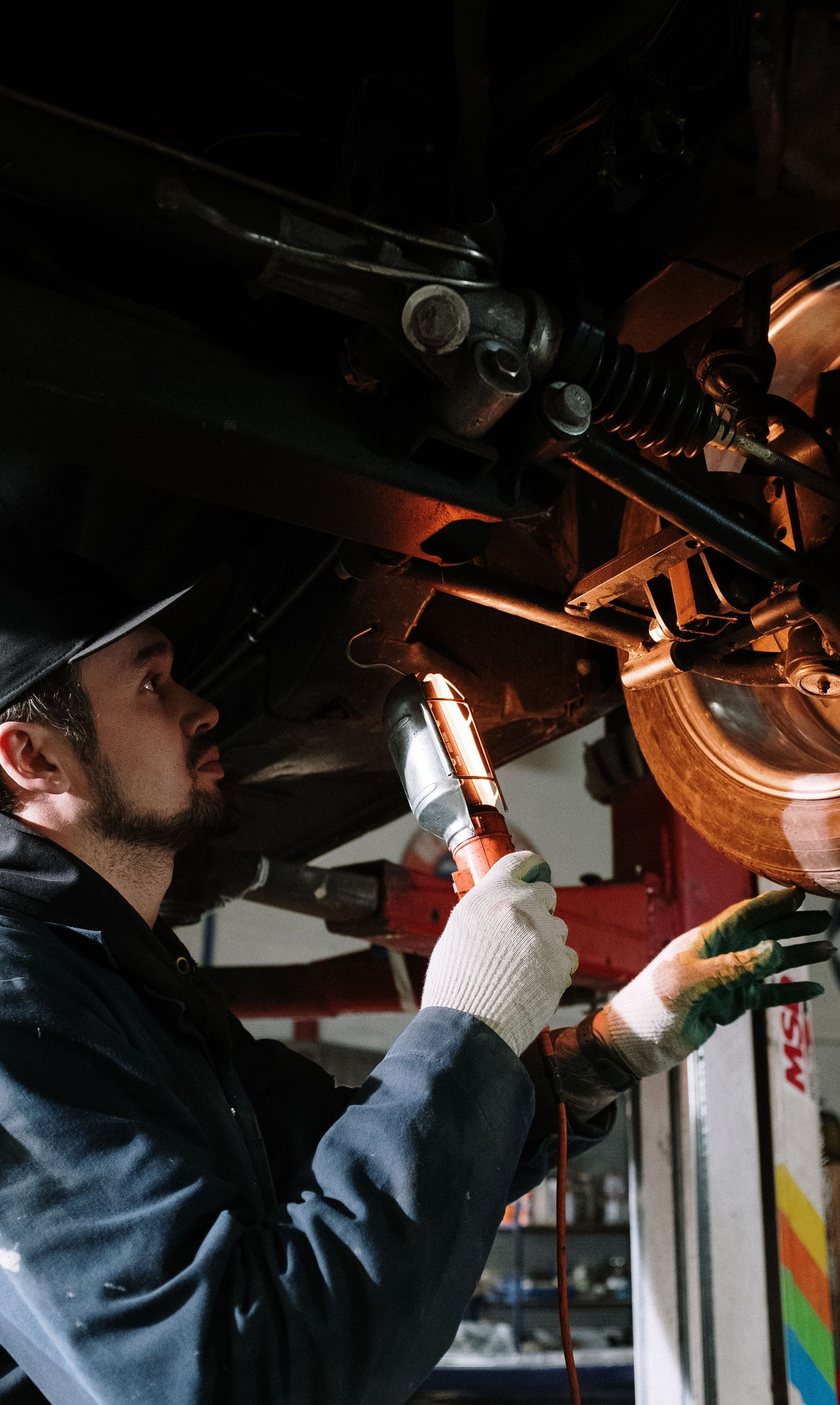 Mechanic inspecting motorcycle engine with a flashlight in a dim garage