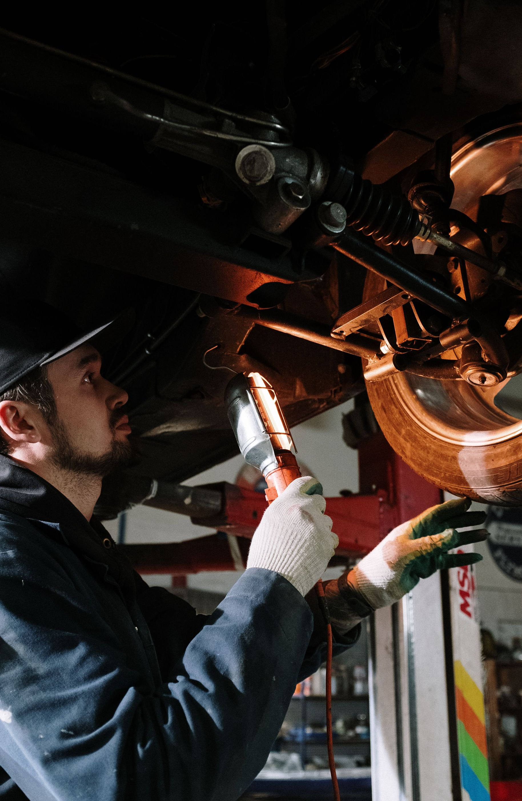 Mechanic inspecting motorcycle engine with a flashlight in a dim garage