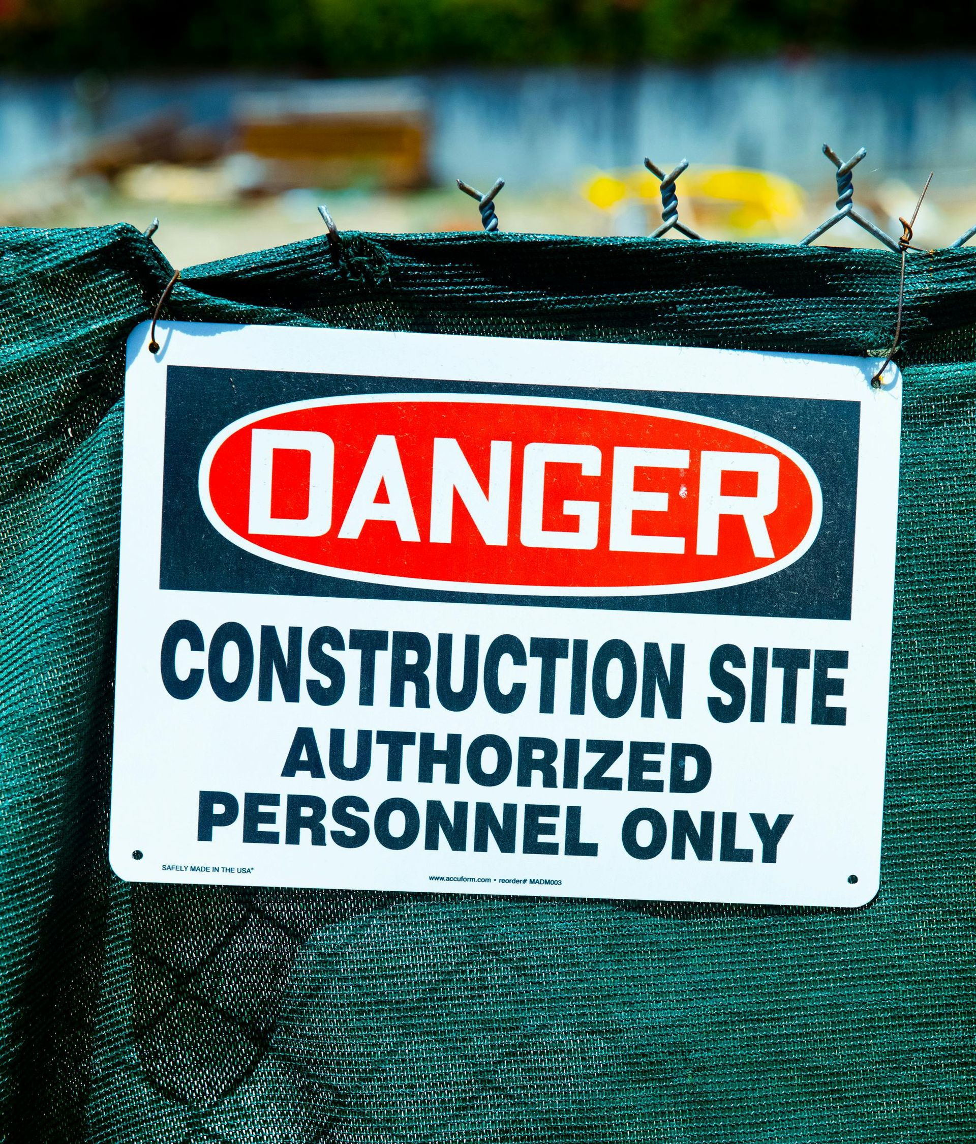 Danger sign on green fence: Construction site, authorized personnel only