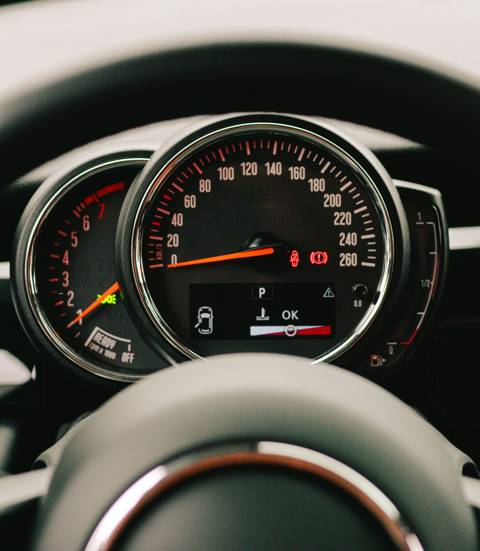 Car dashboard with illuminated speedometer and gauges behind the steering wheel