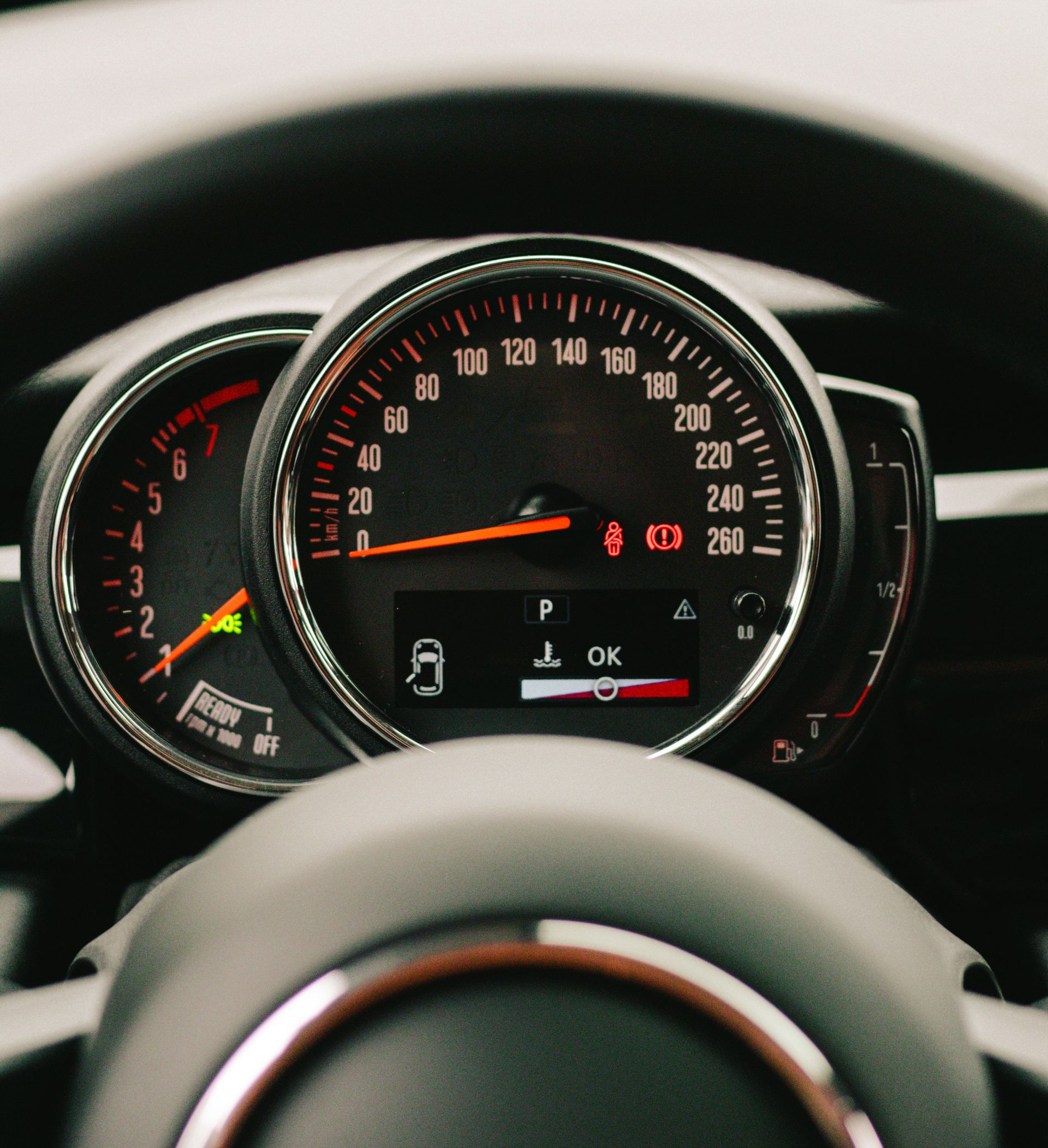 Car dashboard with illuminated speedometer and gauges behind the steering wheel