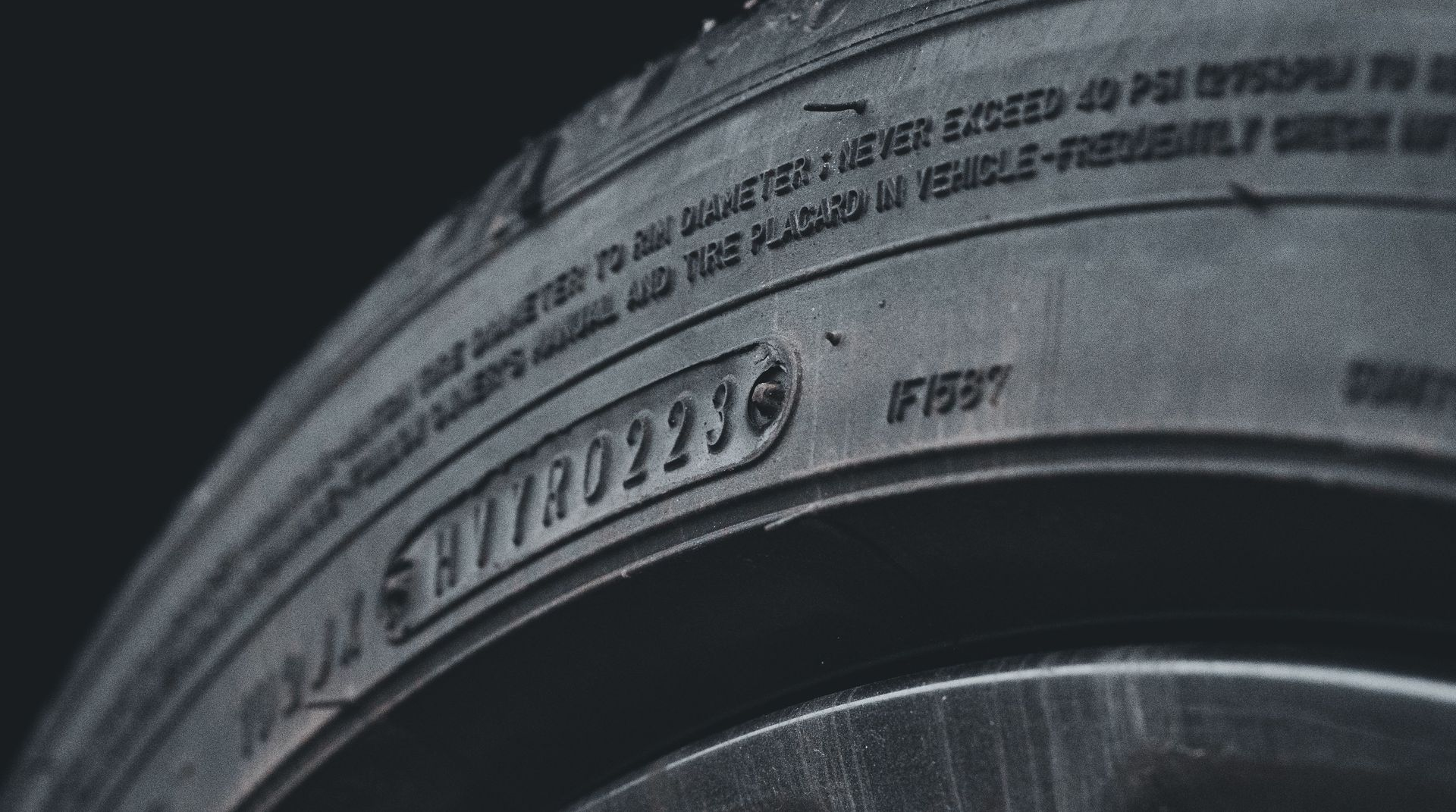 Close-up of a black tire sidewall with embossed numbers and a silver wheel rim edge