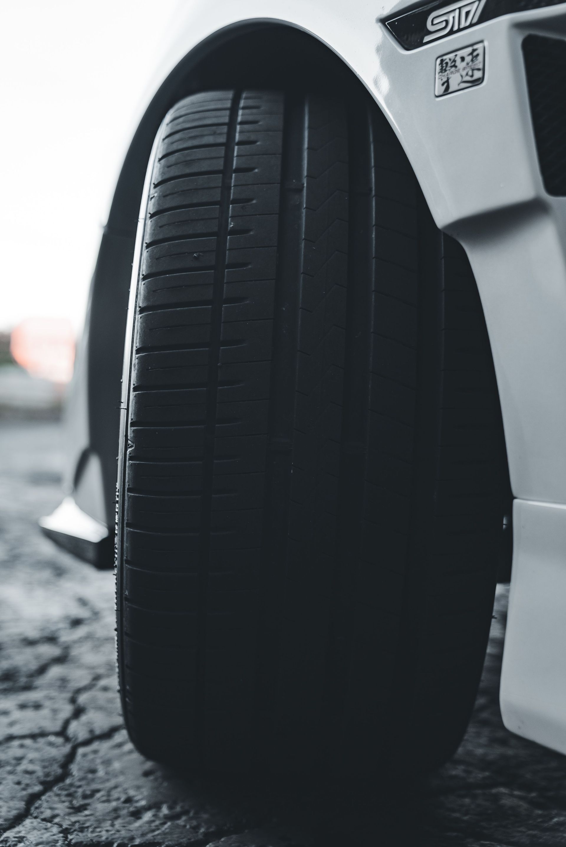 Close-up of a car tire on a snowy road beside a white vehicle