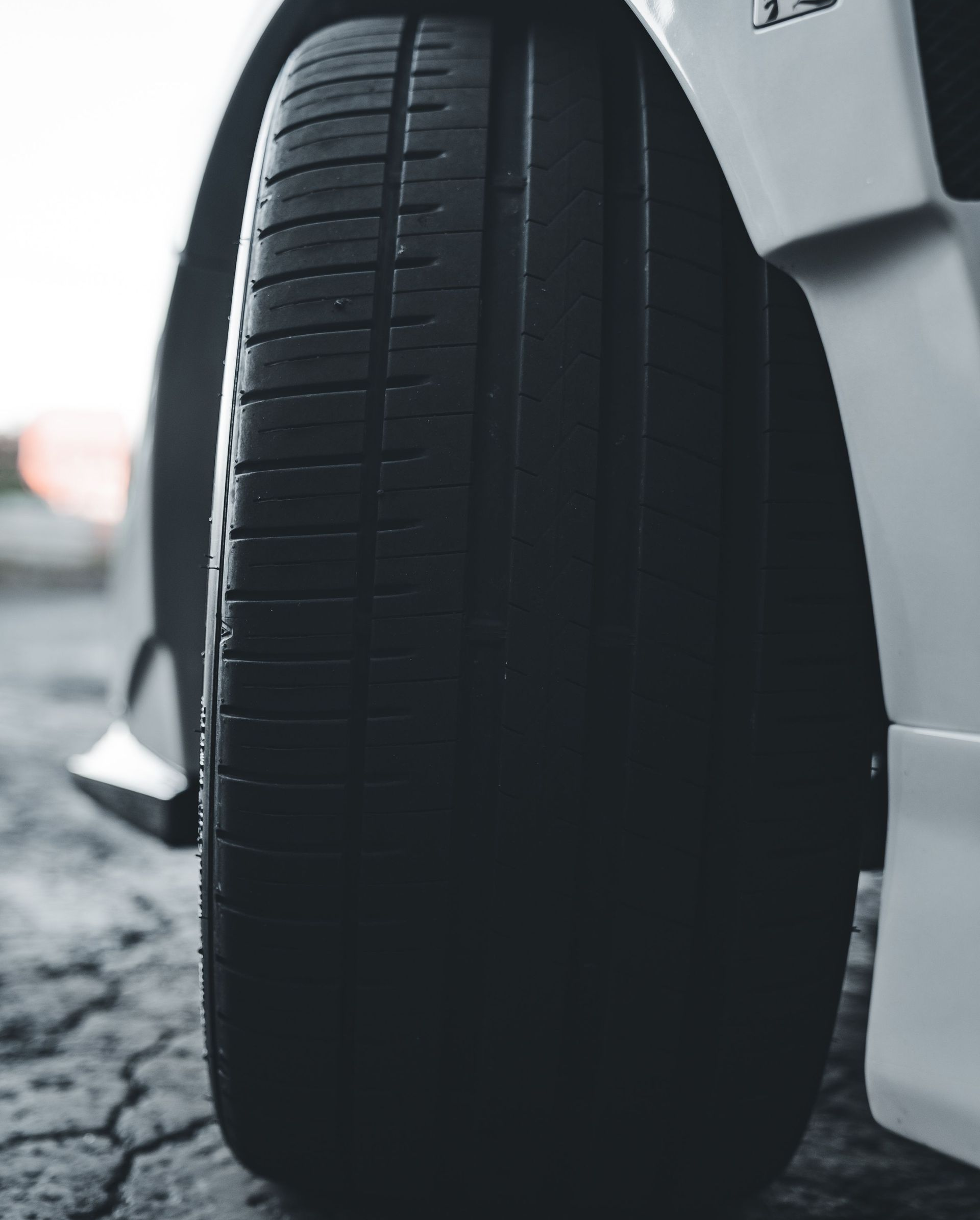Close-up of a car tire on a snowy road beside a white vehicle