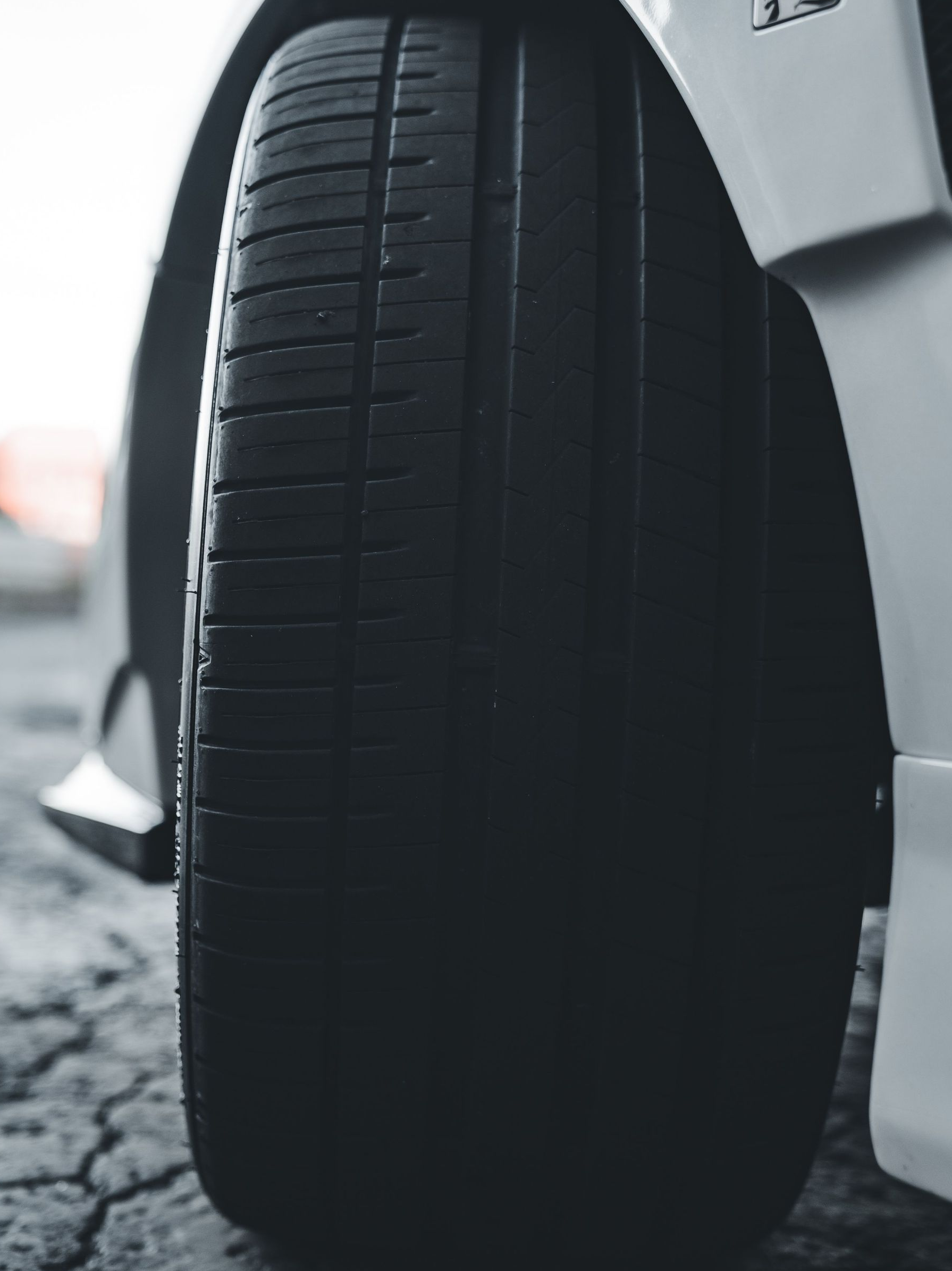 Close-up of a car tire on a snowy road beside a white vehicle