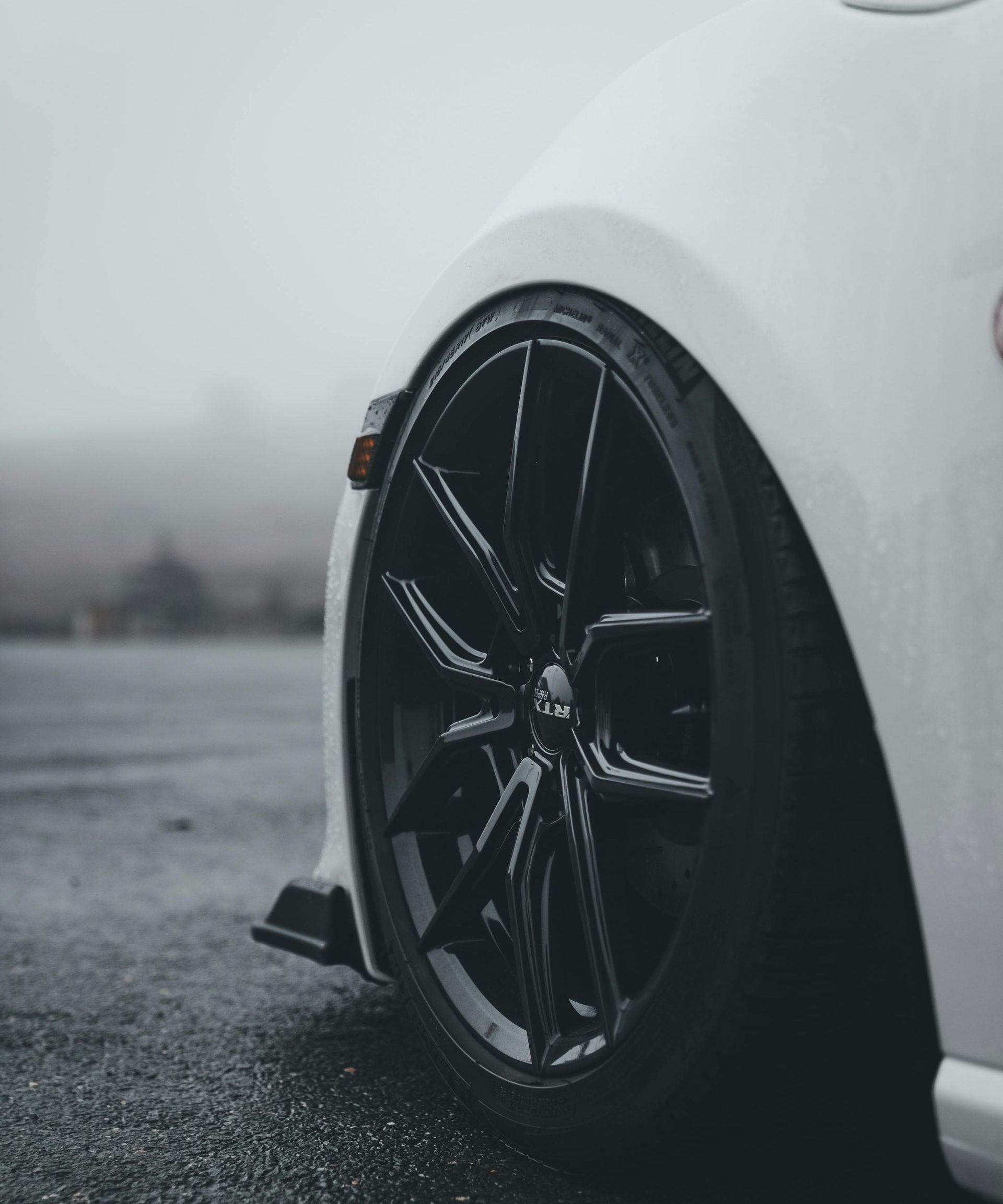 A man is standing next to a tire in front of a pile of tires.