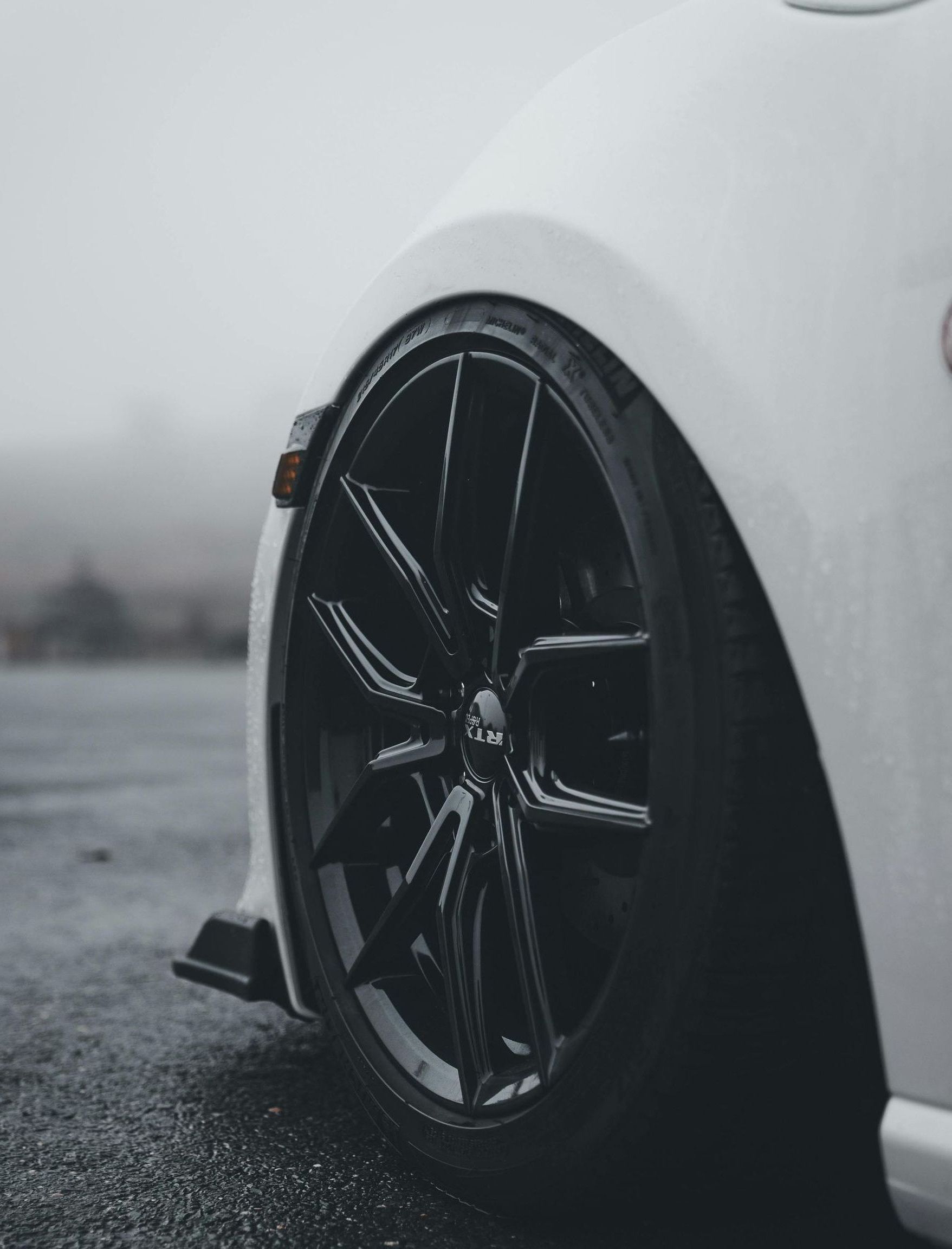 A man is standing next to a tire in front of a pile of tires.