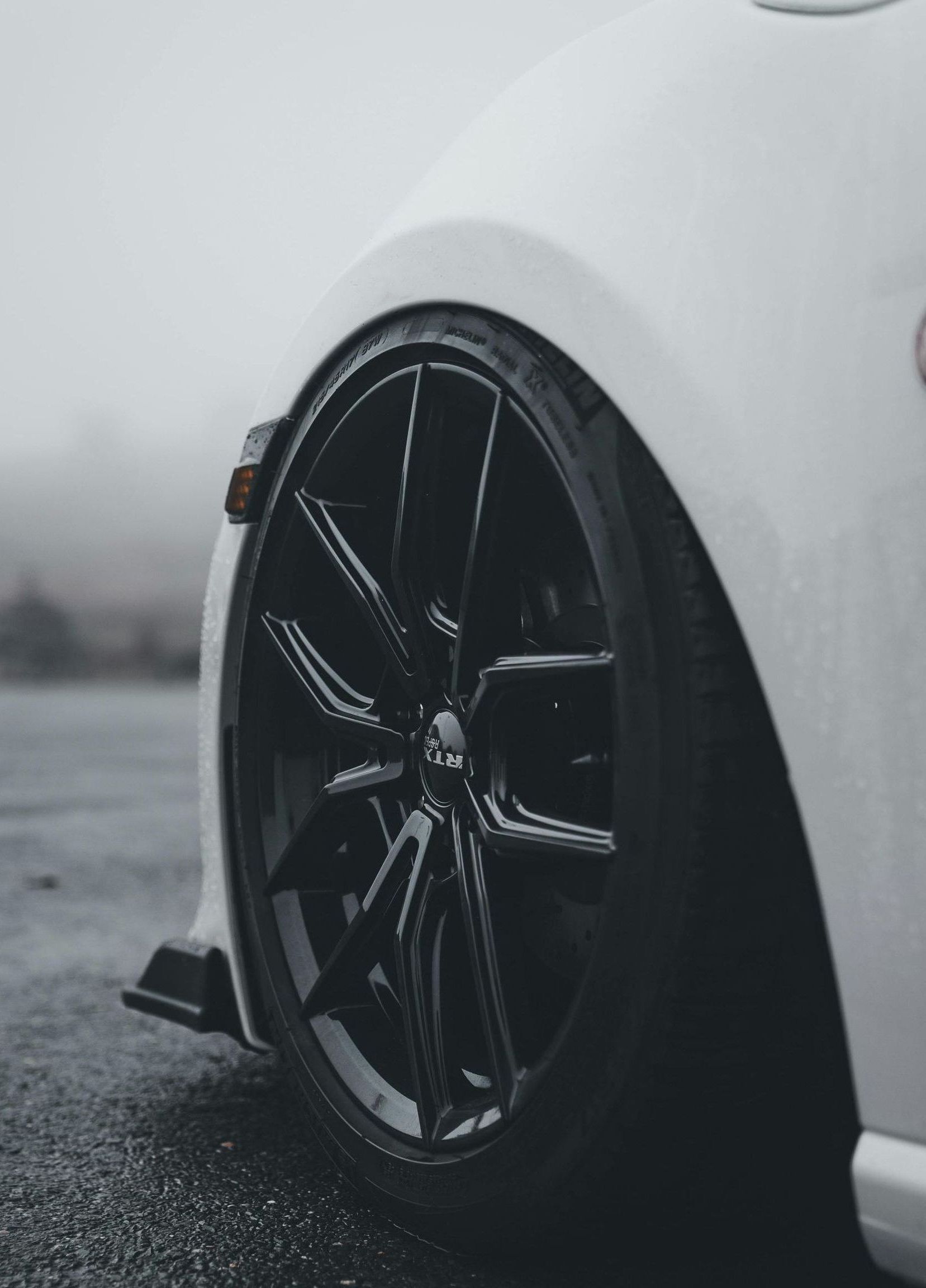 A man is standing next to a tire in front of a pile of tires.