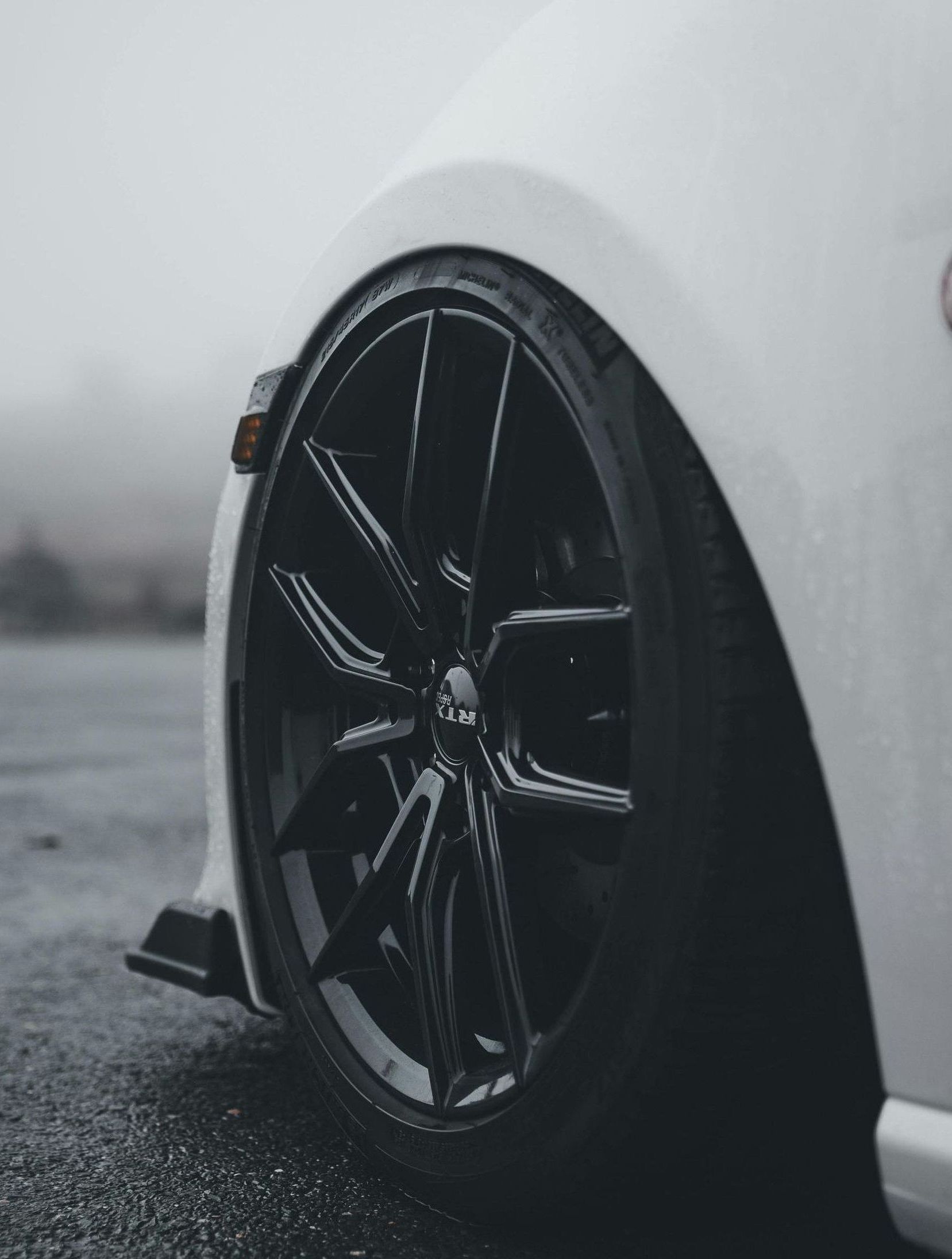 A man is standing next to a tire in front of a pile of tires.