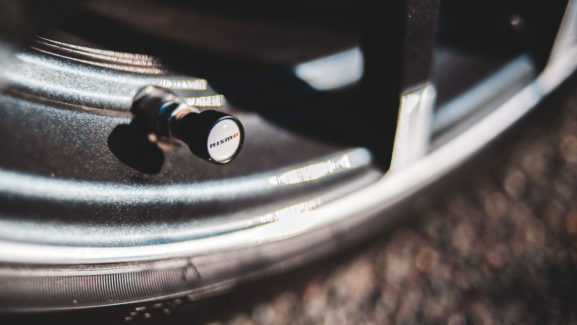 Close-up of a car wheel rim with a black tire valve stem cap.