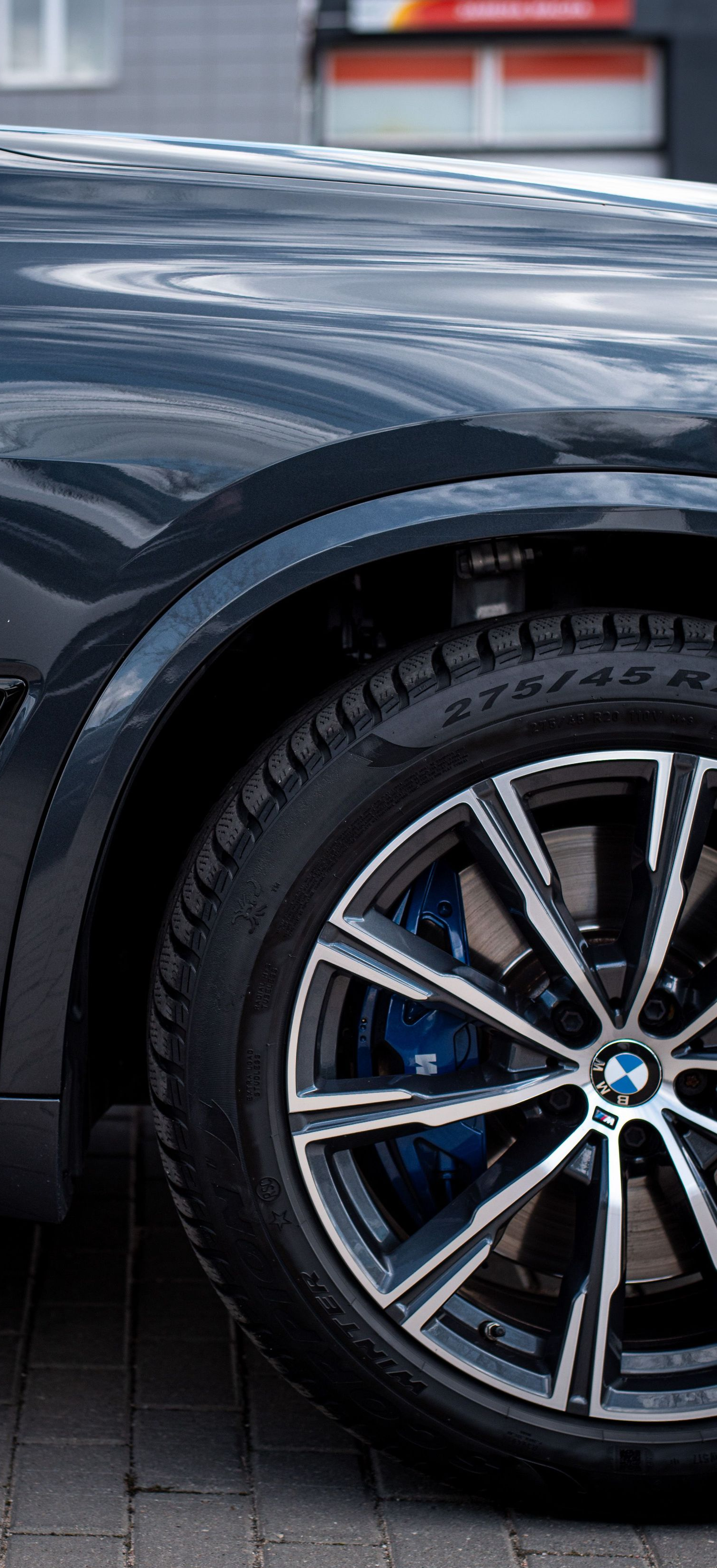 Close-up of a dark blue sports car’s front wheel and fender with M badge