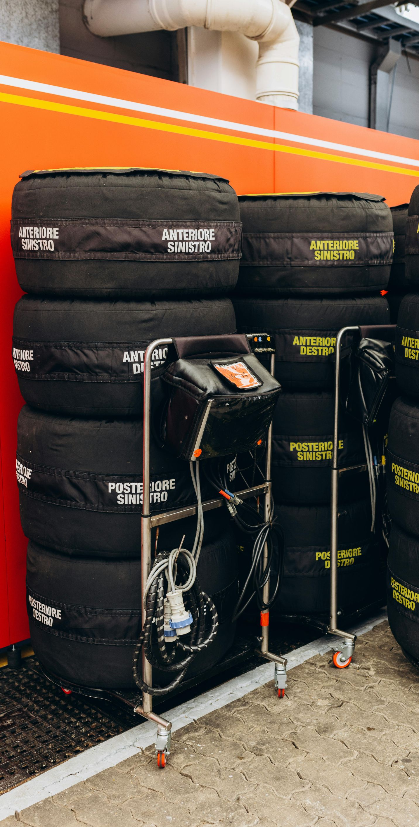 Stacks of black racing tires on metal carts inside a garage.