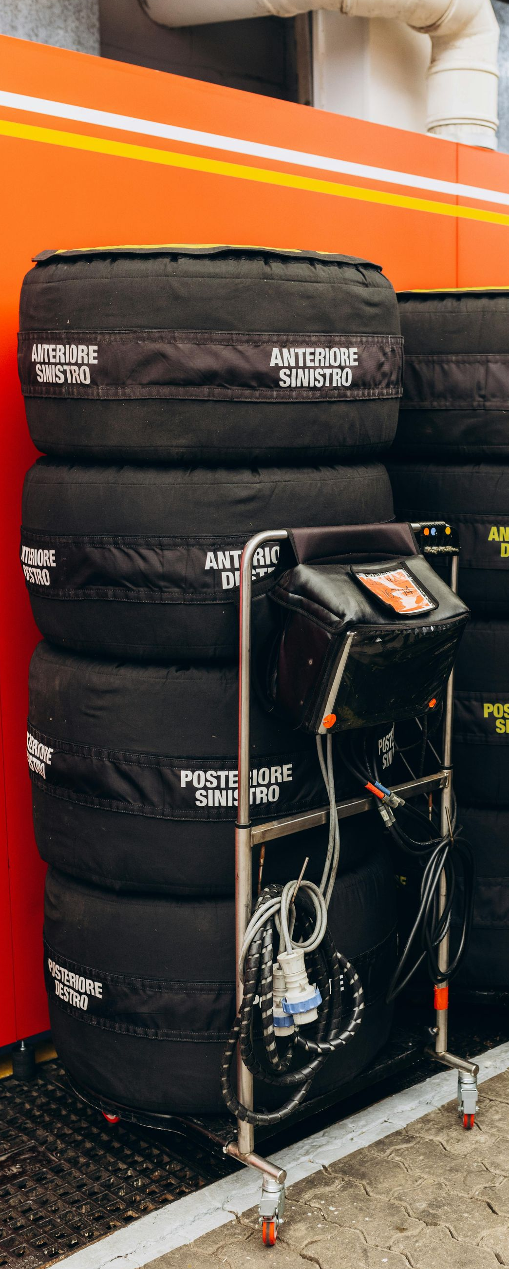 Stacks of black racing tires on metal carts inside a garage.
