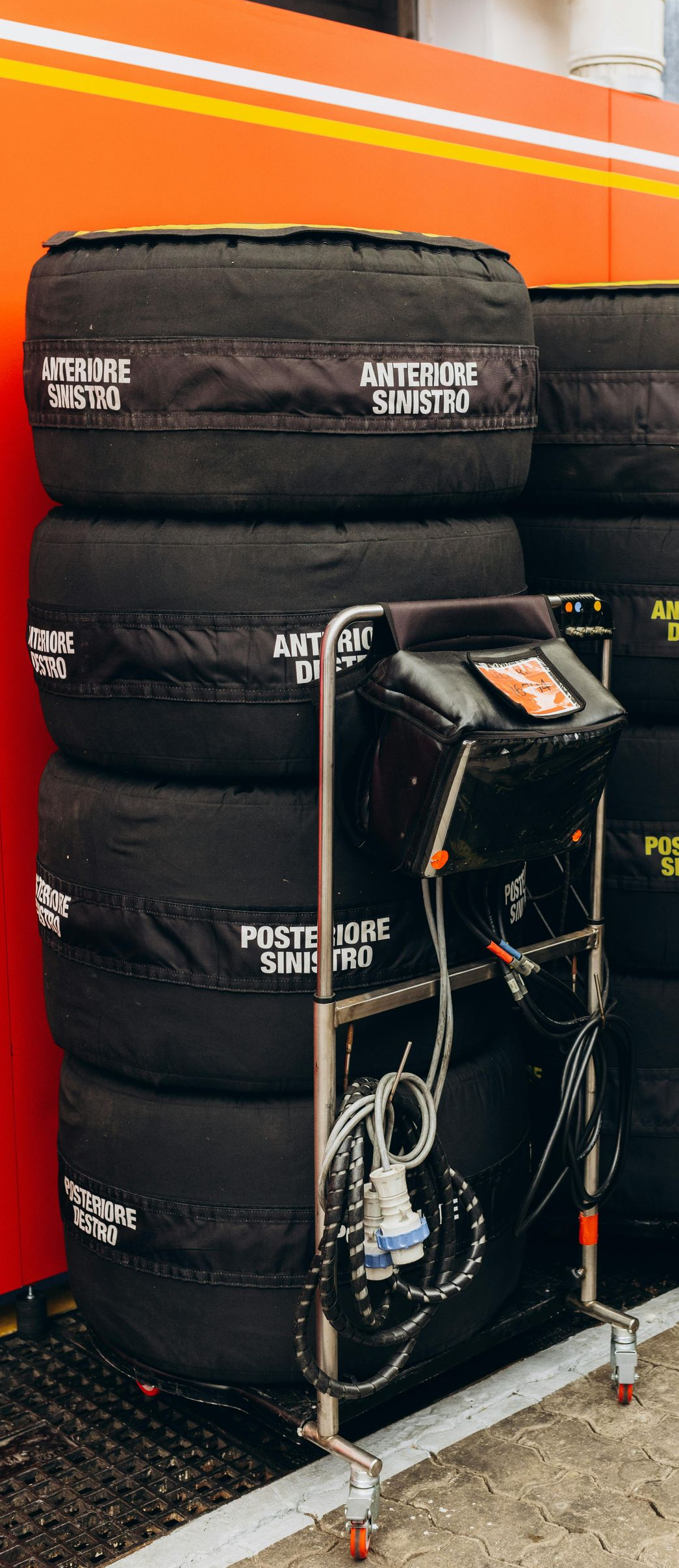 Stacks of black racing tires on metal carts inside a garage.