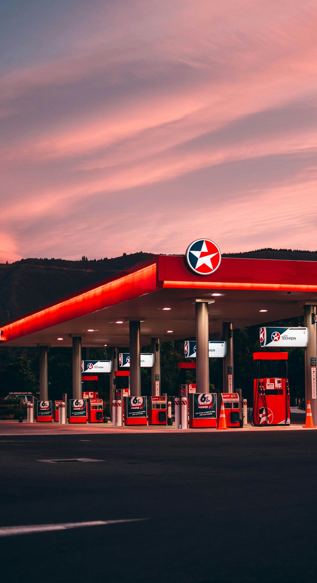 Gas station with red canopy and Texaco sign at sunset.