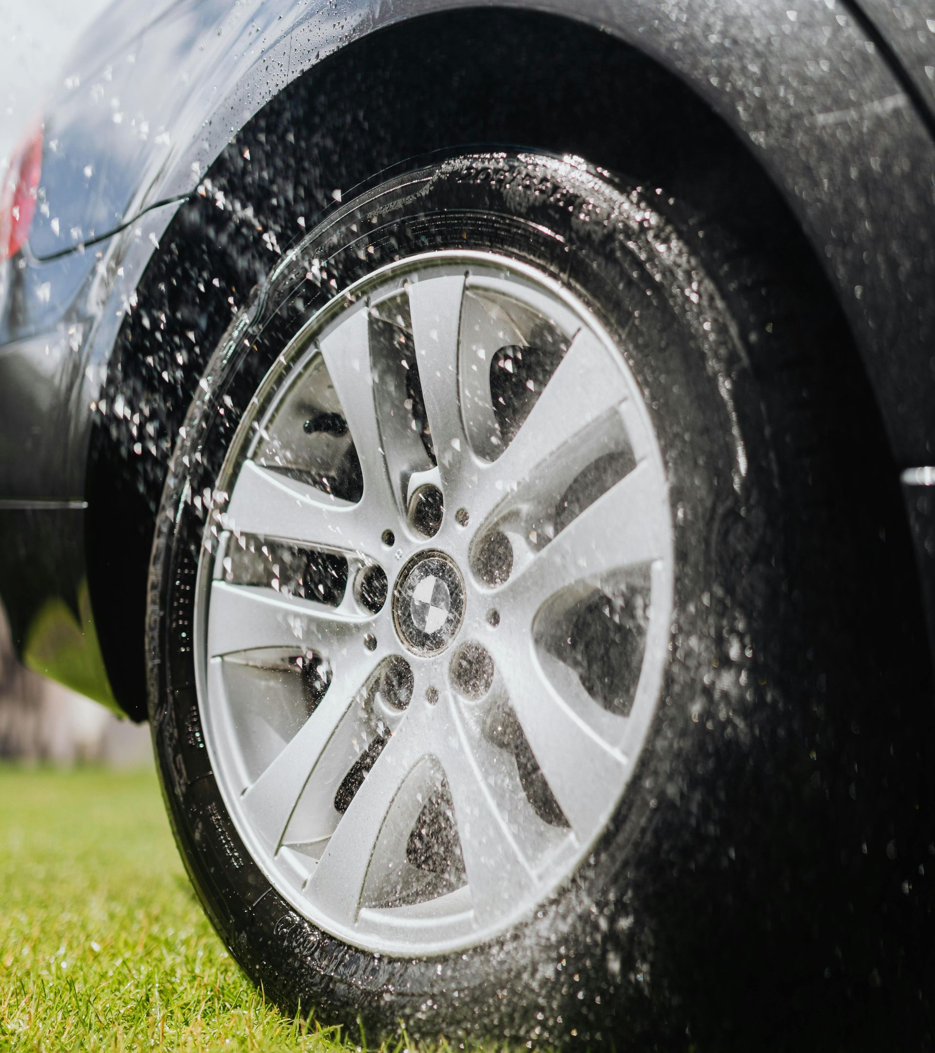 Car tire being sprayed with water and suds during washing.