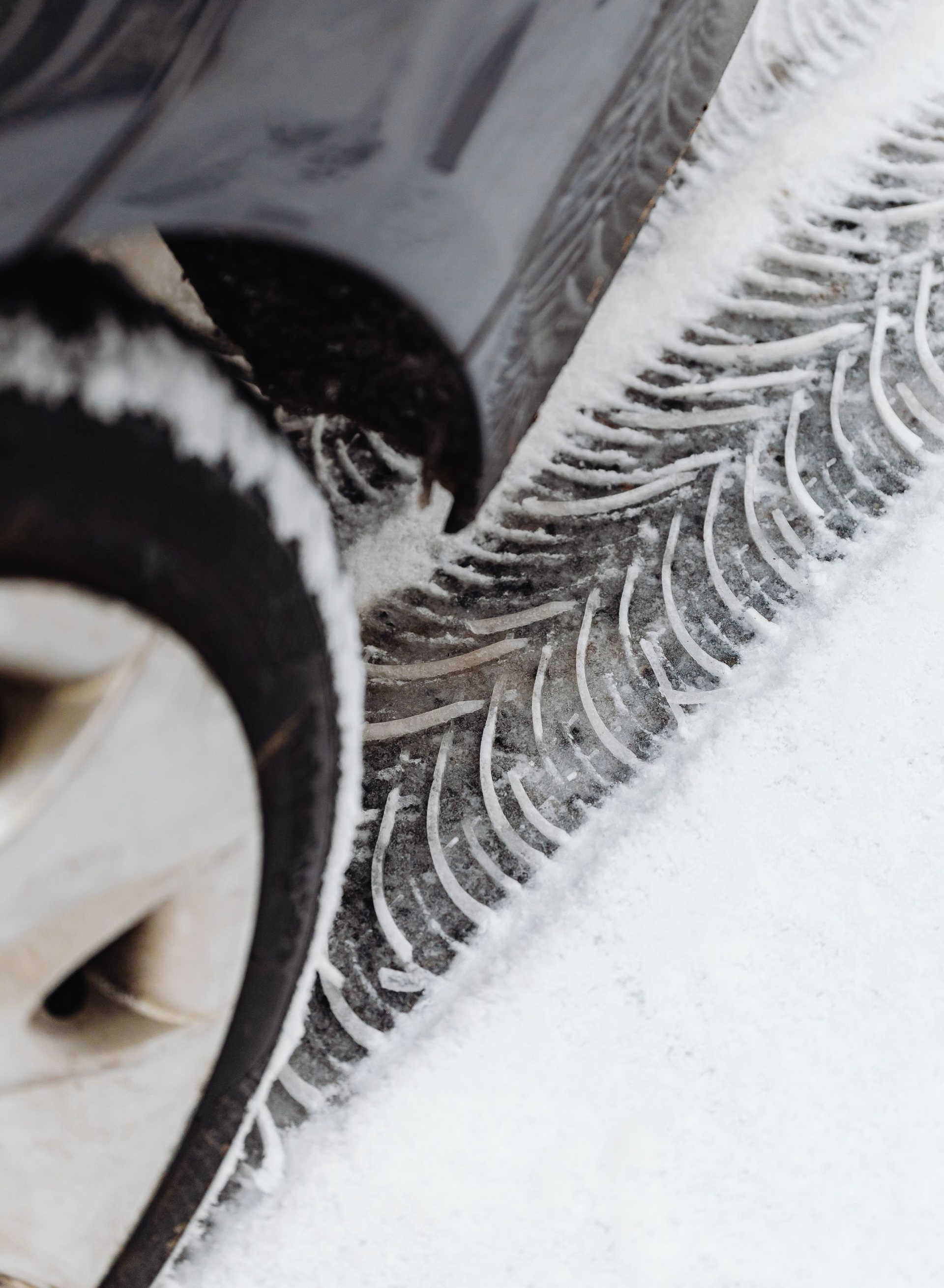 Car tire on a snow-covered road, with snow spray around the wheel well