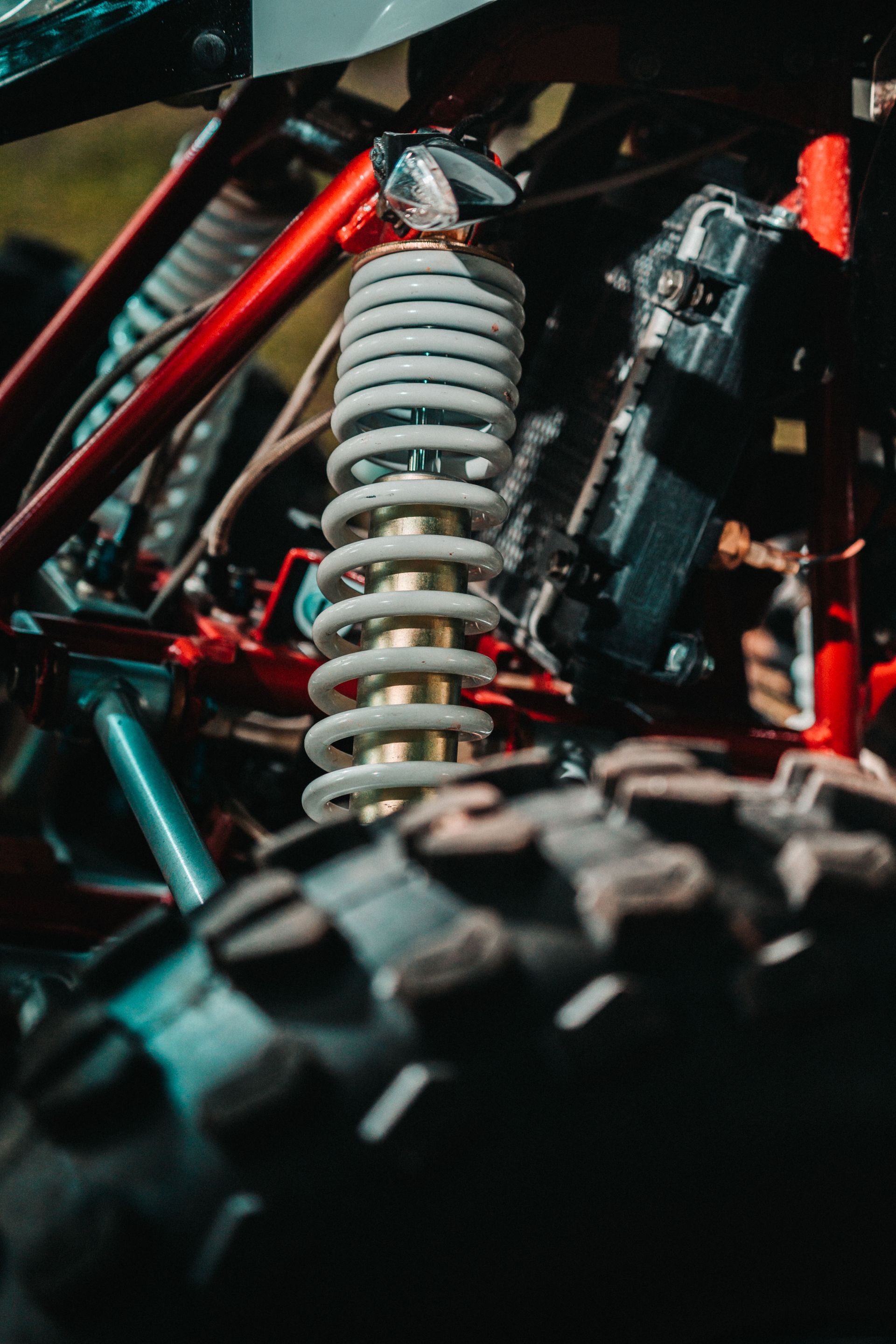 Close-up of an off-road vehicle’s suspension coil spring and tire in red and gray.