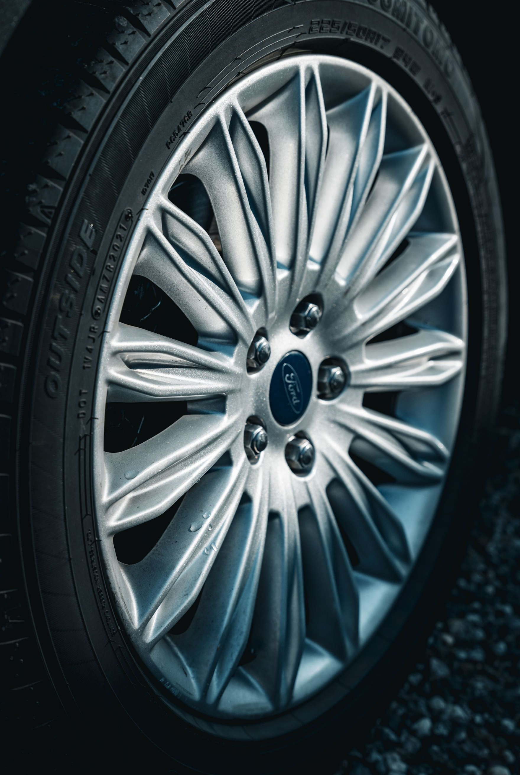 Close-up of a silver car wheel and tire on a dark road surface