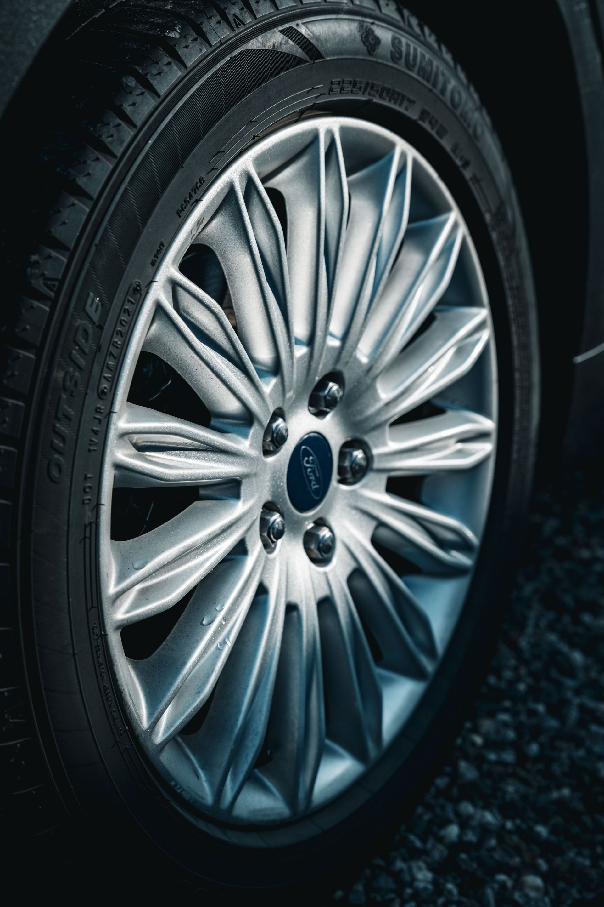Close-up of a silver car wheel and tire on a dark road surface