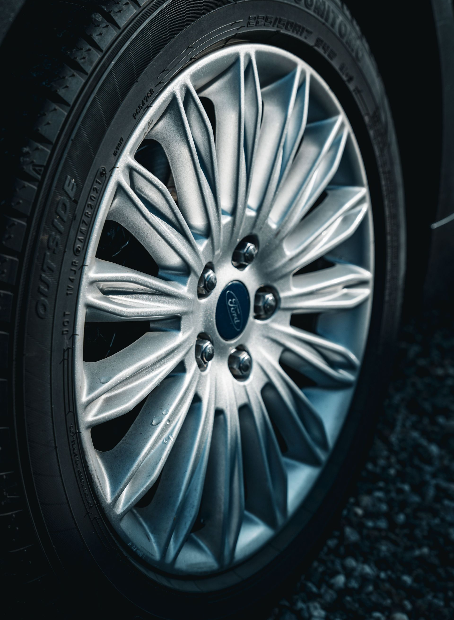 Close-up of a silver car wheel and tire on a dark road surface