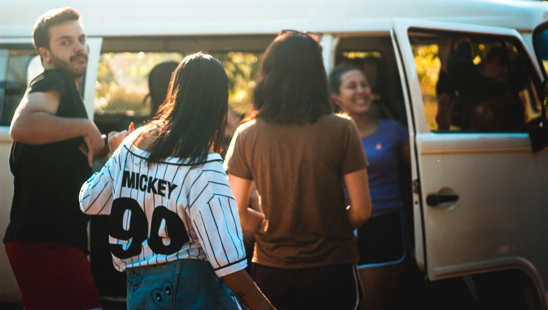 People boarding a white van at sunset, with one person carrying a number 99 jersey