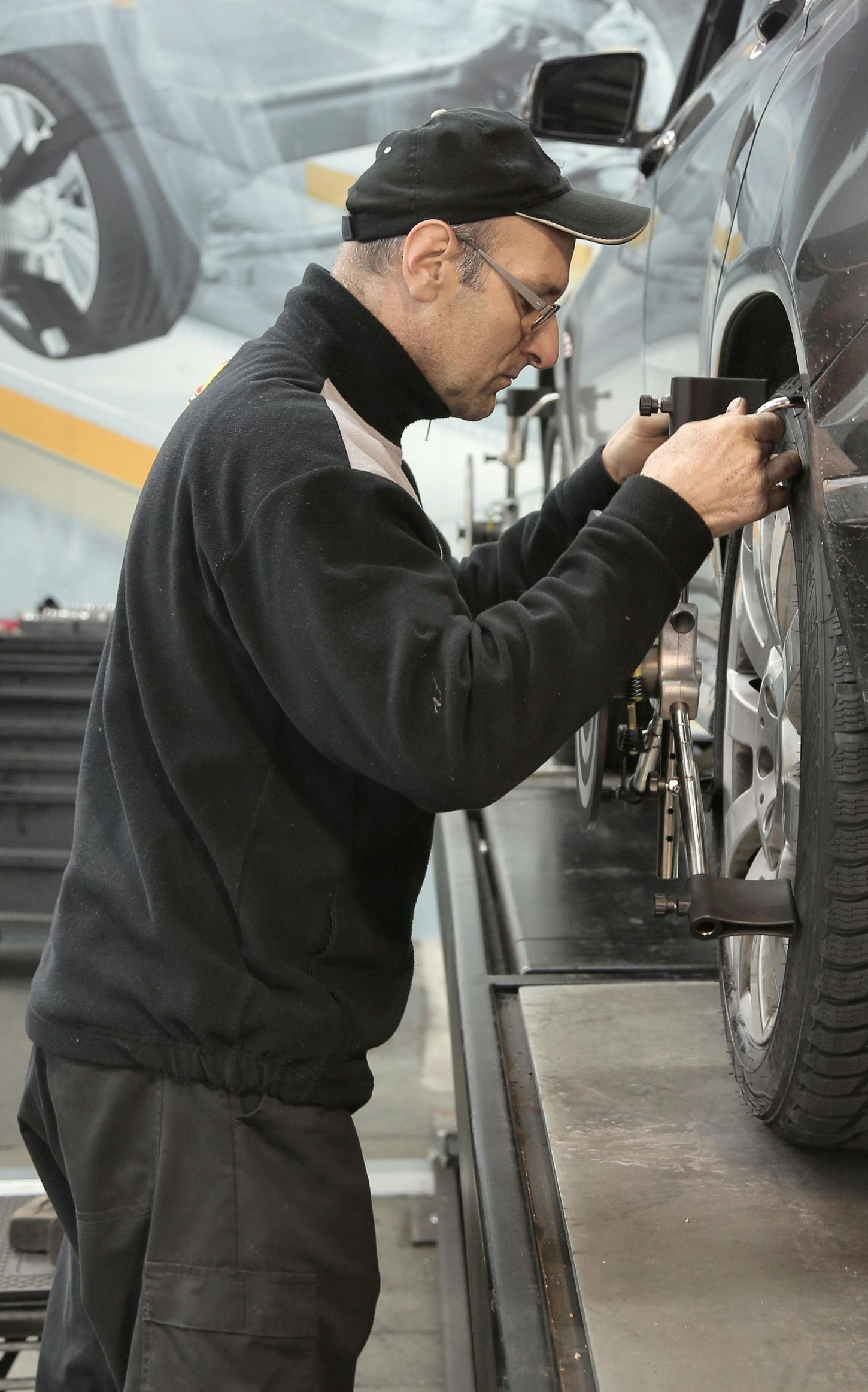 Mechanic aligning a car tire in a repair shop.