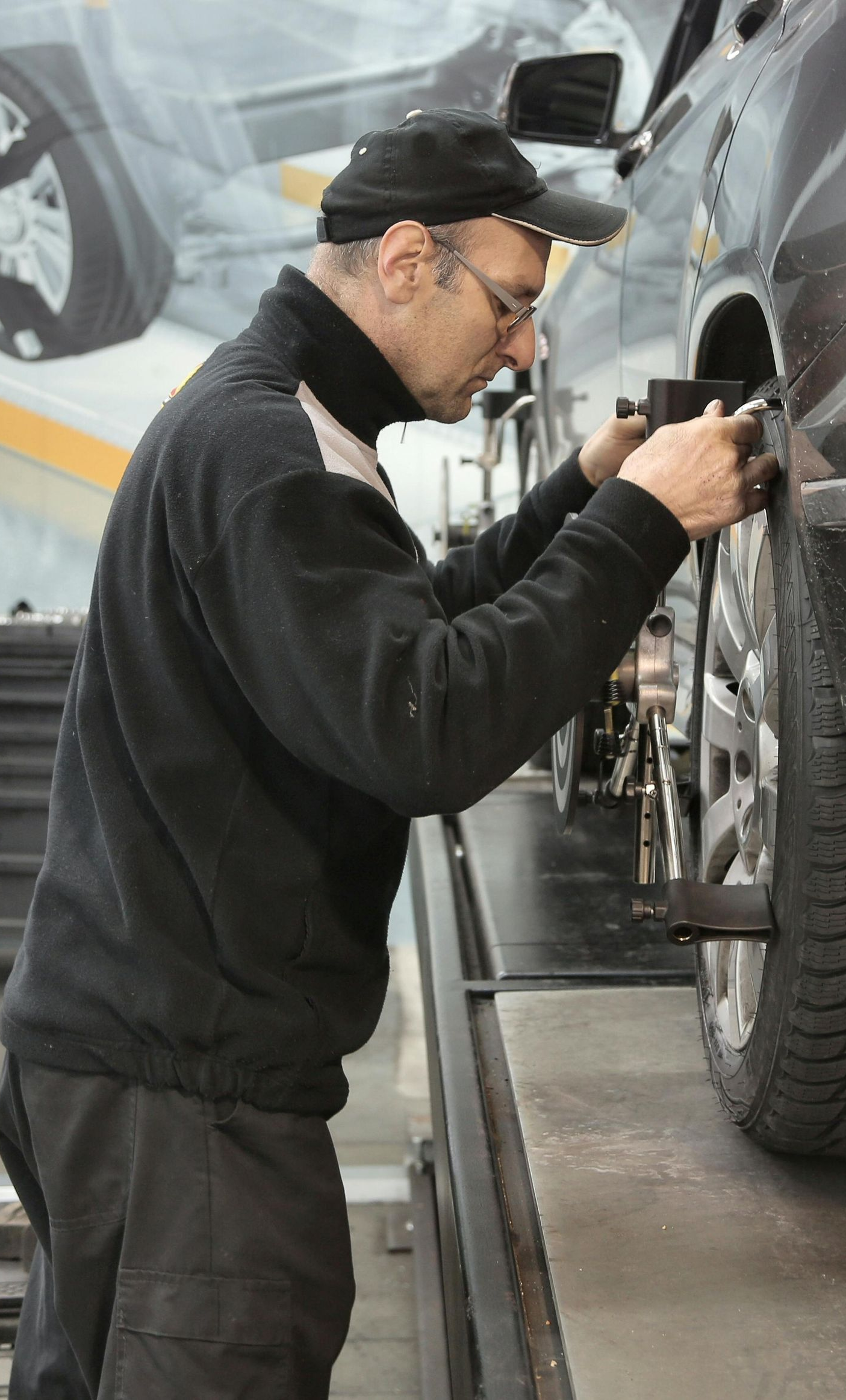 Mechanic aligning a car tire in a repair shop.