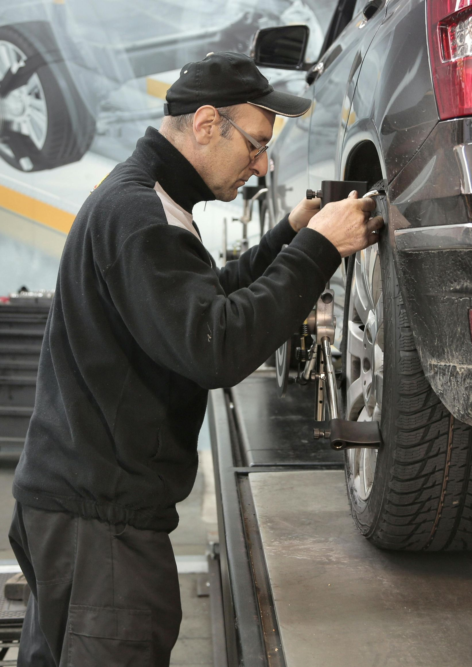 Mechanic aligning a car tire in a repair shop.