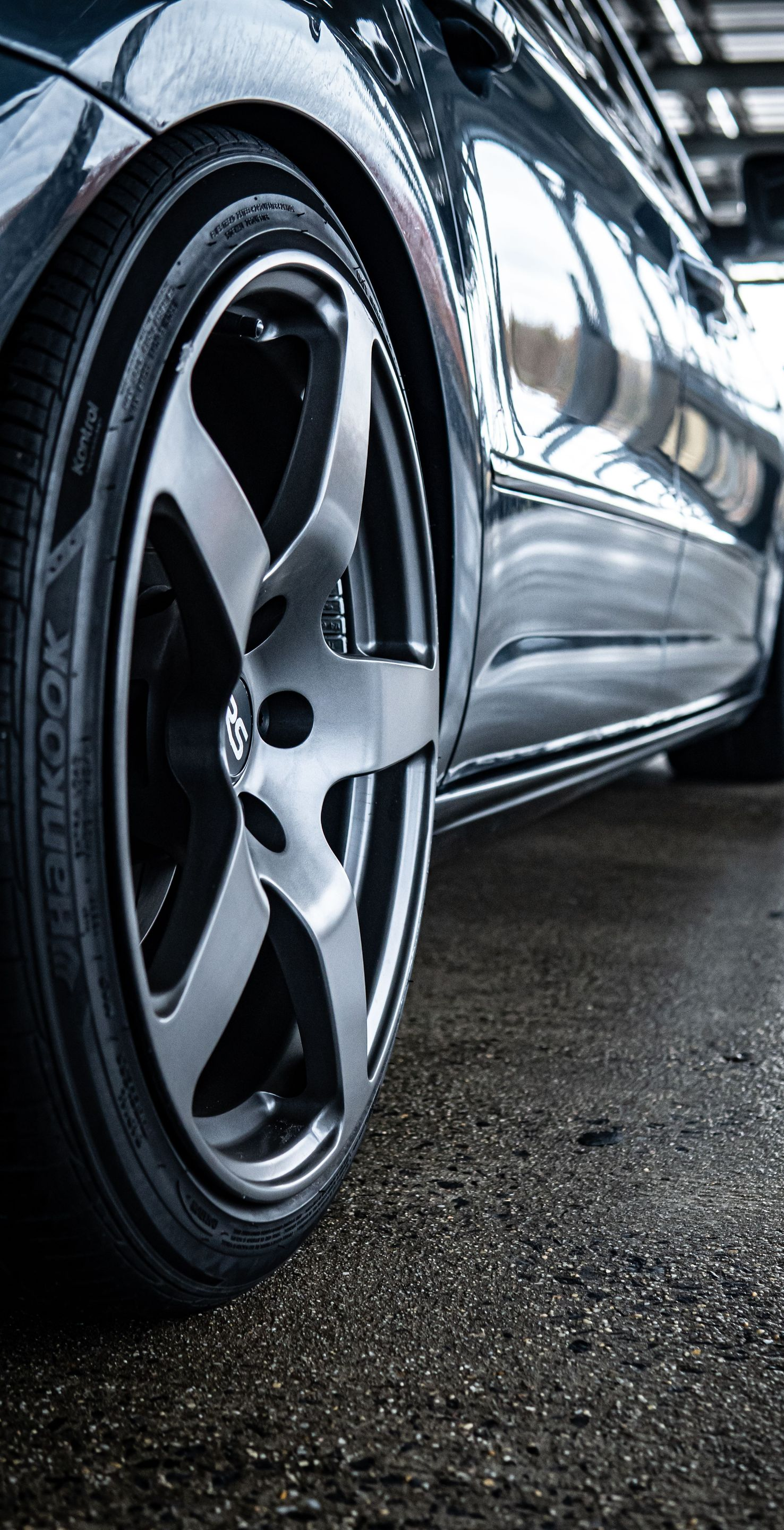 Close-up of a shiny black sports car wheel on a wet garage floor