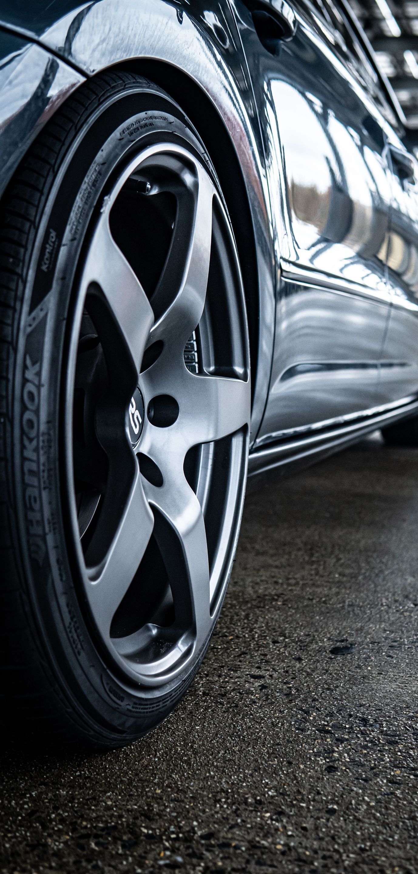 Close-up of a shiny black sports car wheel on a wet garage floor