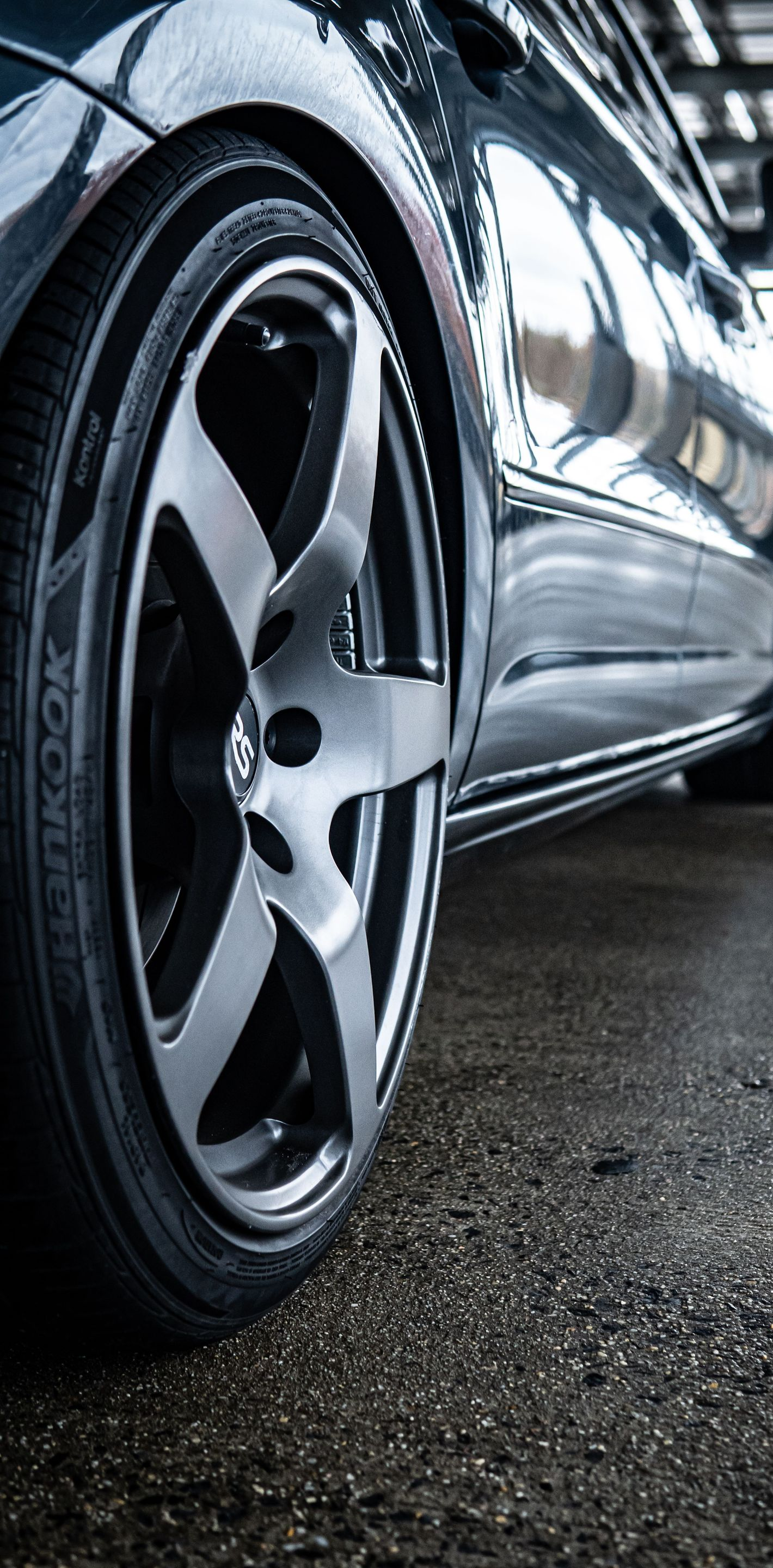 Close-up of a shiny black sports car wheel on a wet garage floor