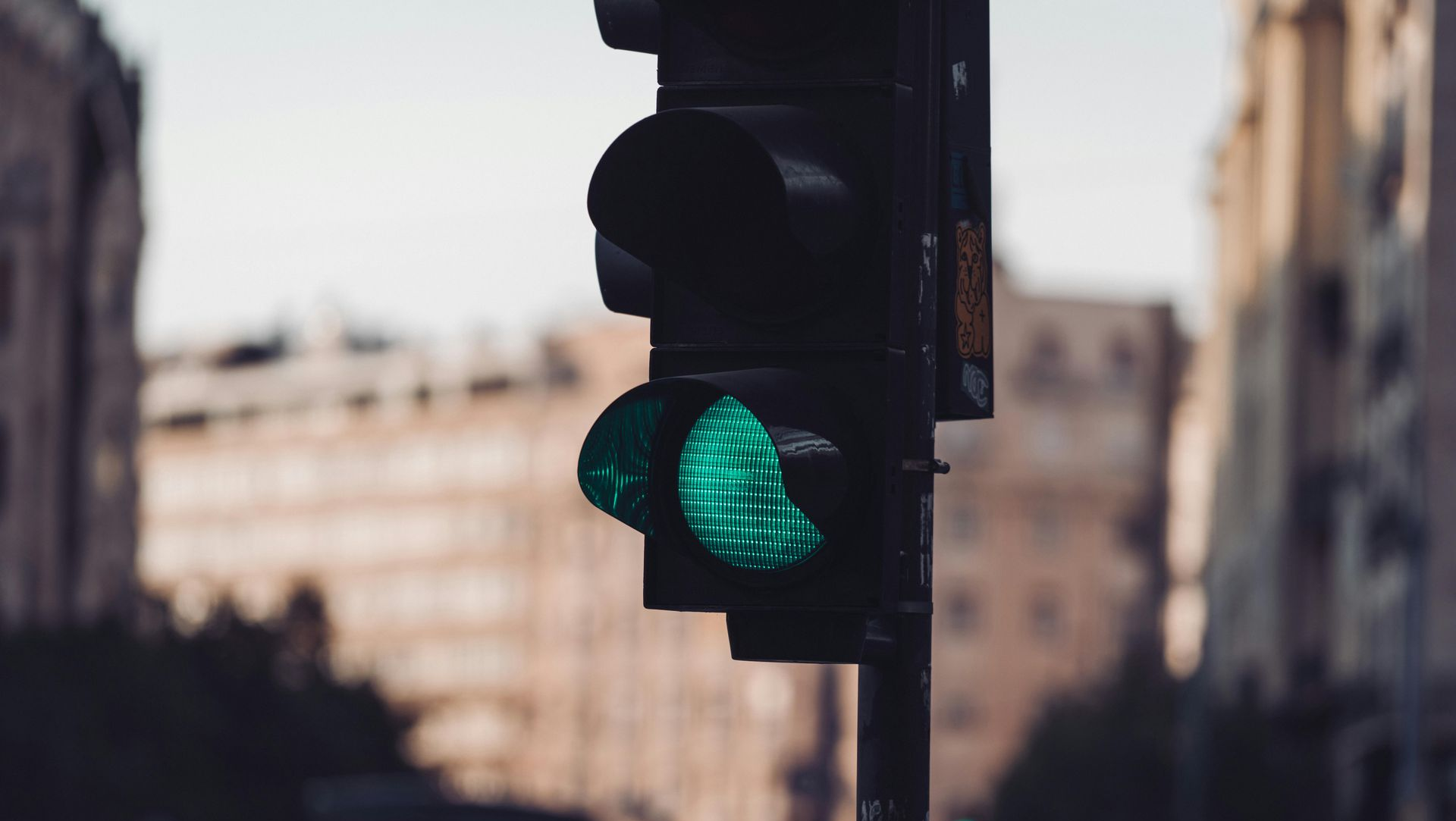 Green traffic light glowing on a city street with blurred buildings in the background
