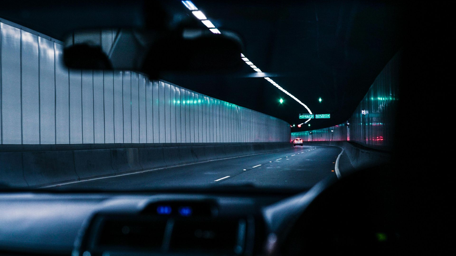 Car interior view driving through a dark tunnel with lights.