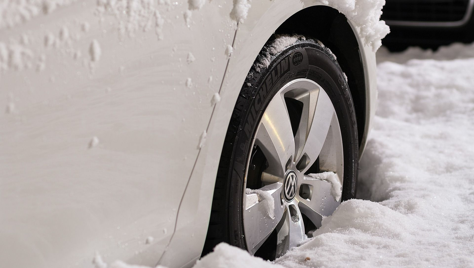 White car wheel stuck in deep snow.