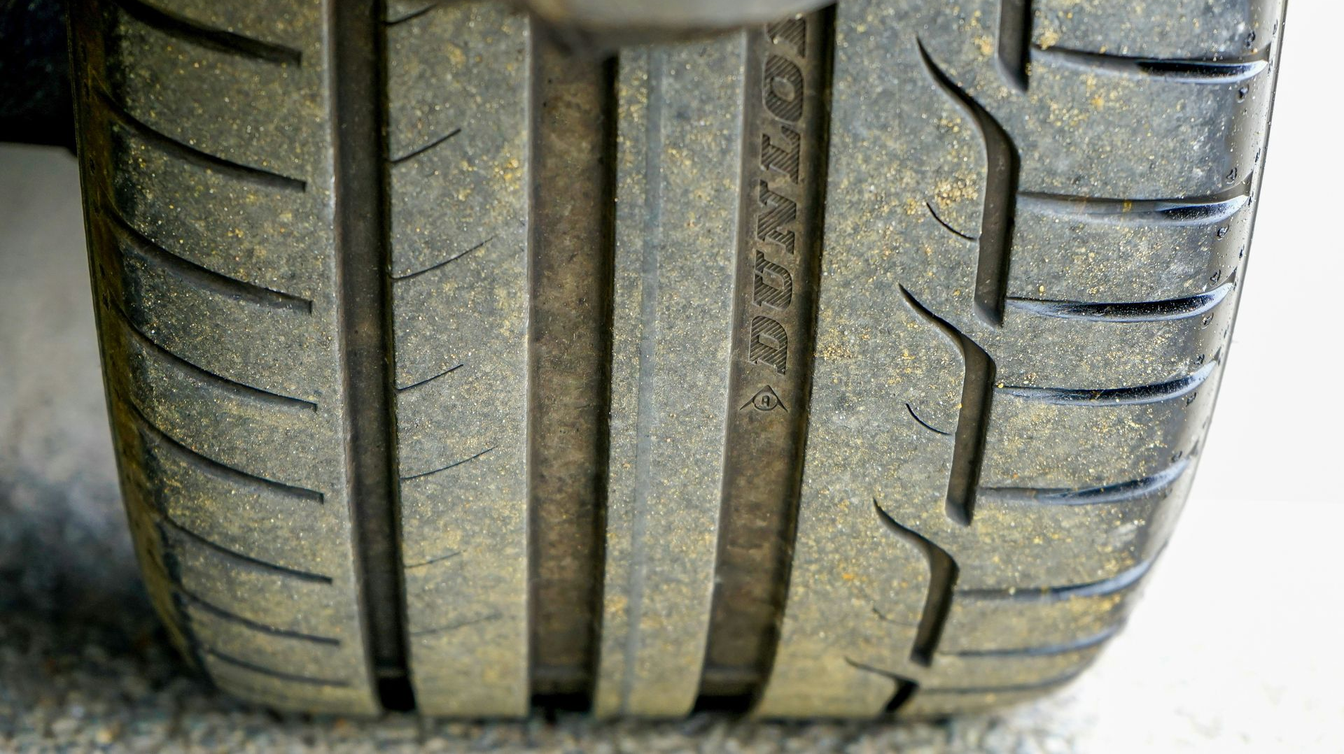 Close-up of a worn car tire tread with visible grooves and a slightly flattened center
