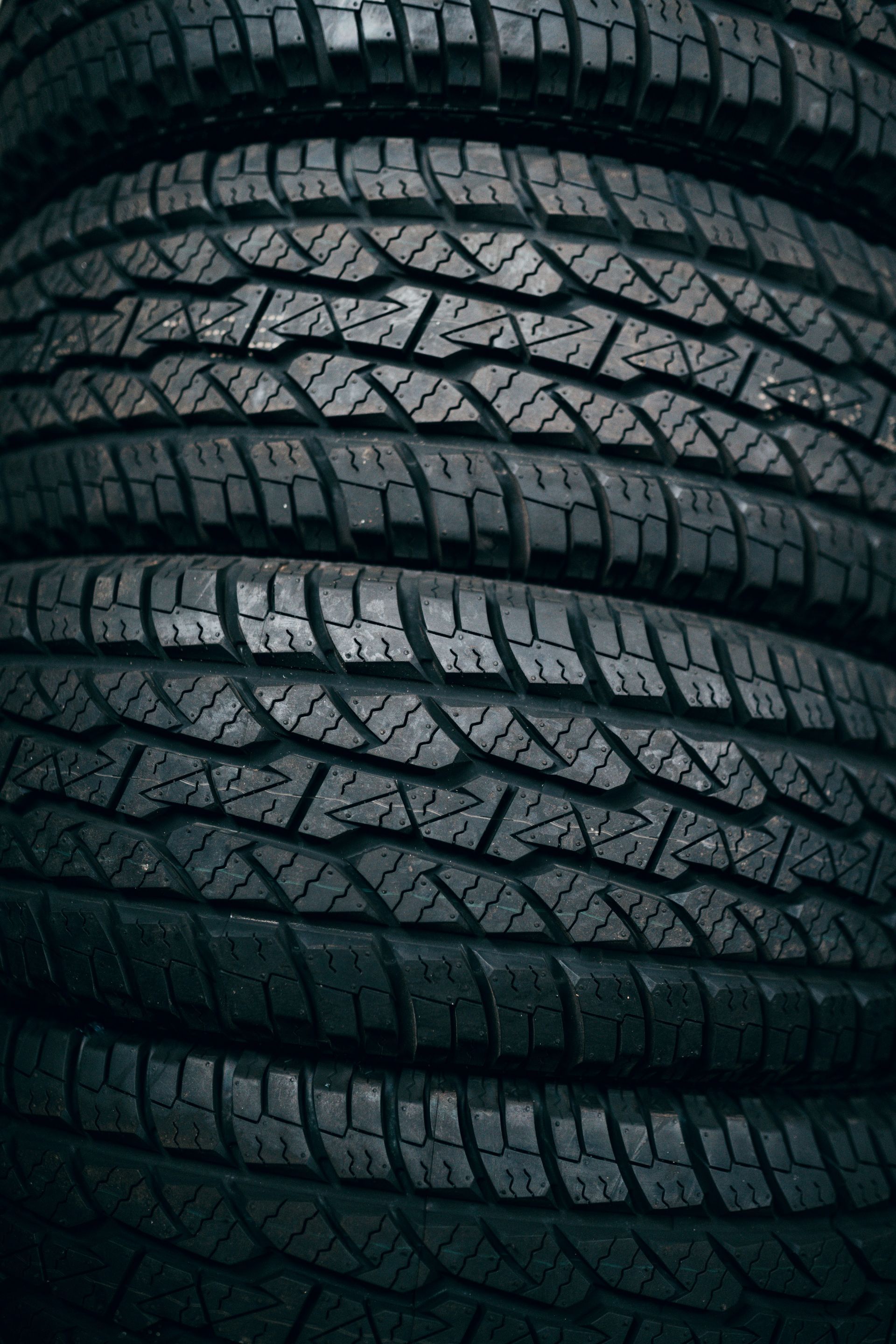 Stacked black car tires with deep tread patterns