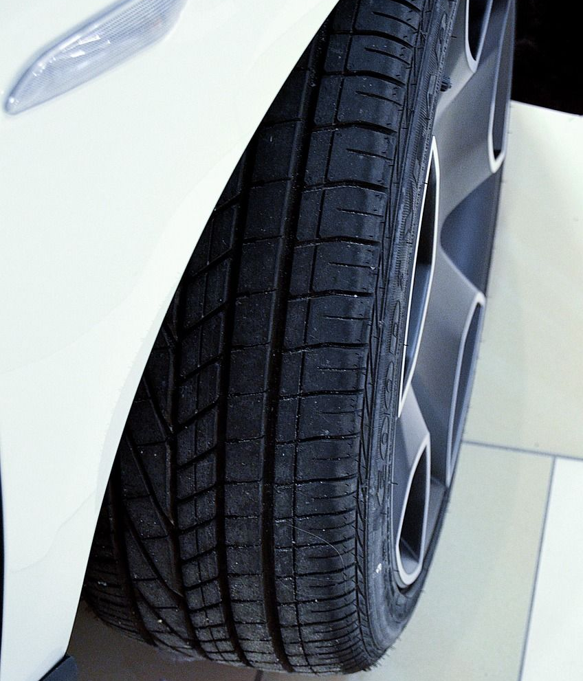Close-up of a white car's tire and wheel; the tire has a black tread pattern.