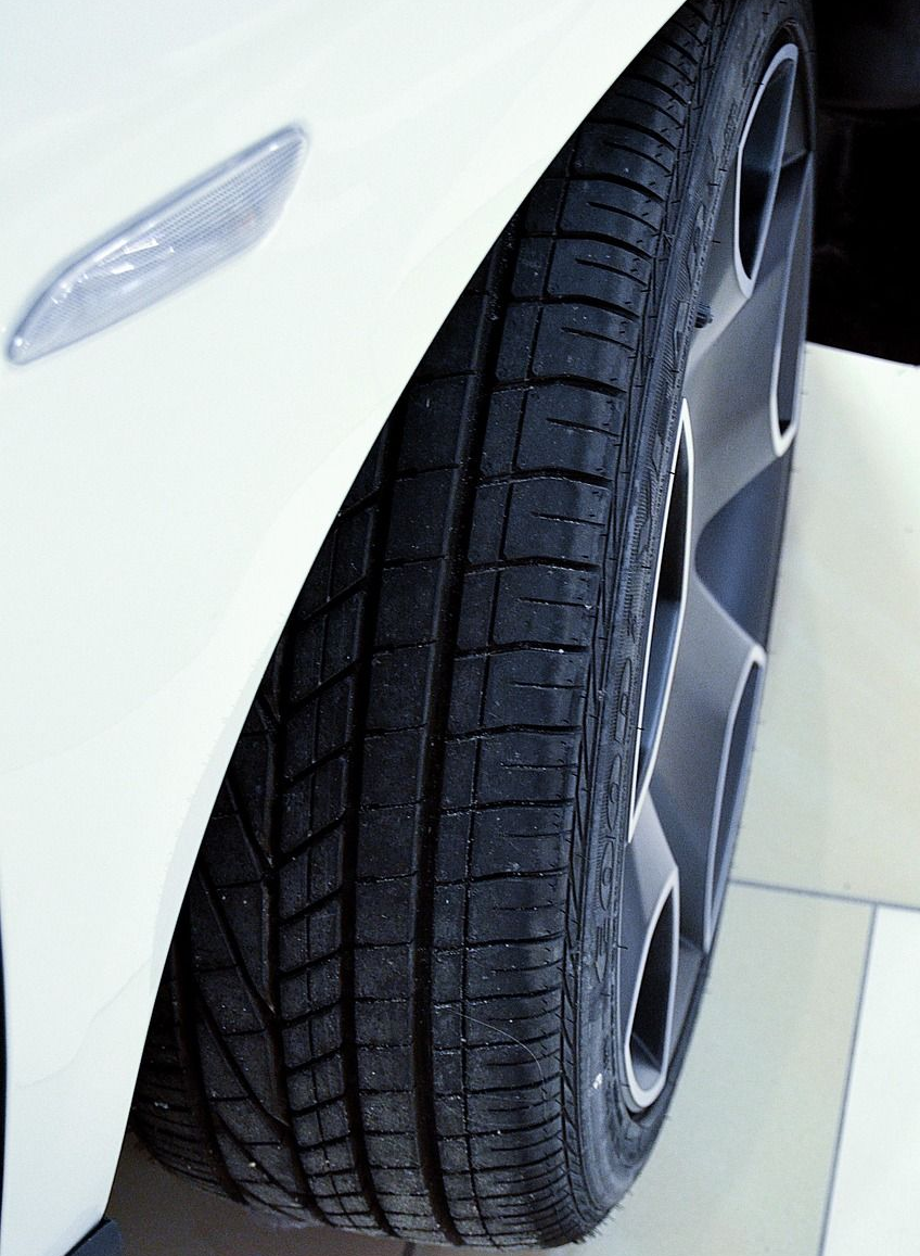 Close-up of a white car's tire and wheel; the tire has a black tread pattern.