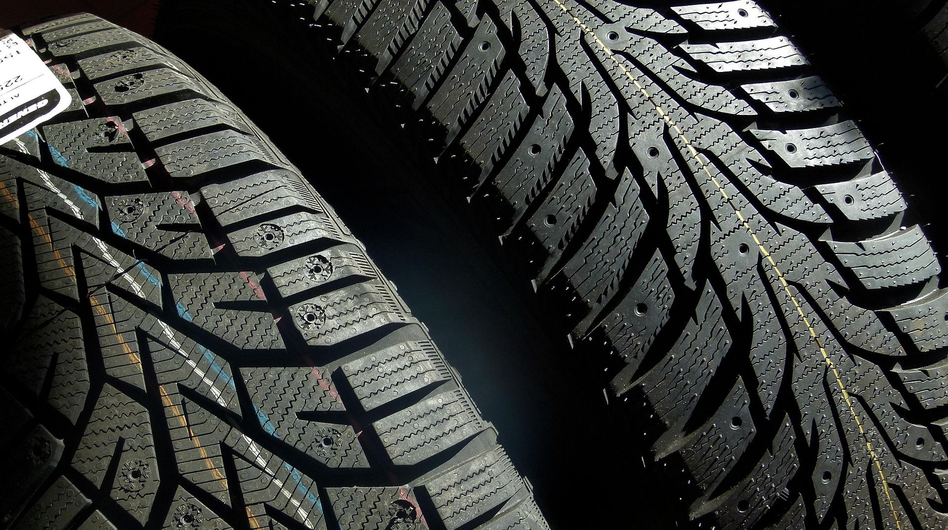 Close-up view of two black car tires with deep treads, likely winter tires.