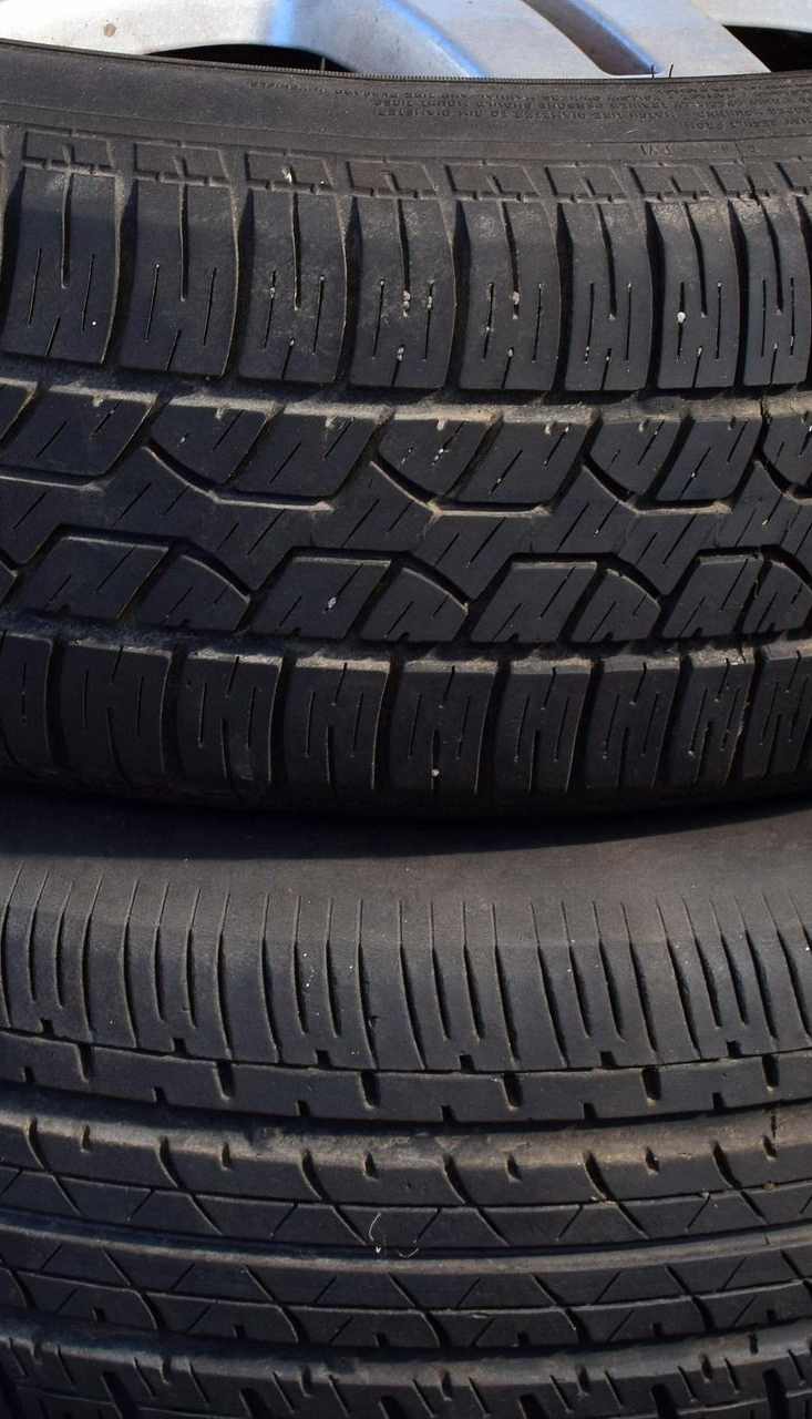Two stacked black tires with textured treads, resting indoors.