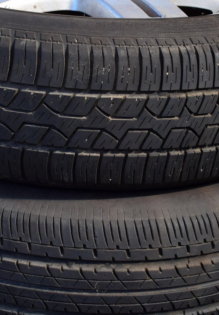 Two stacked black tires with textured treads, resting indoors.