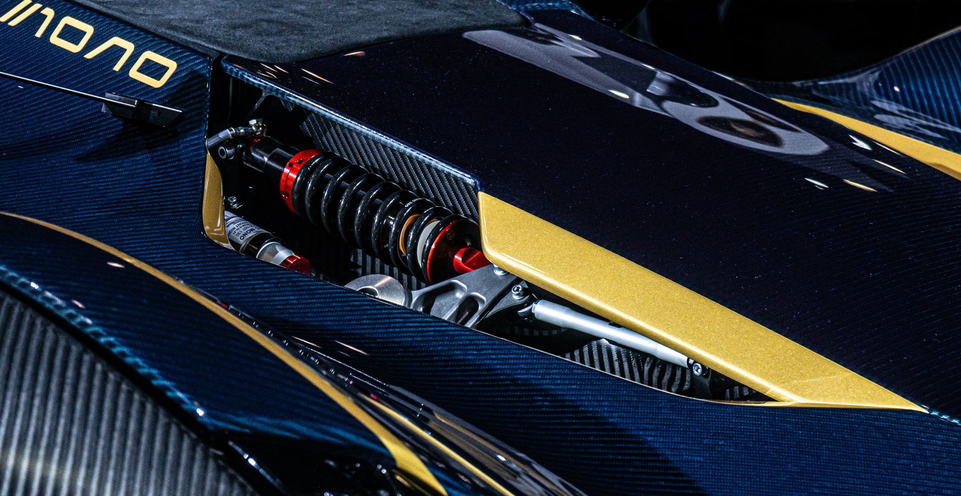 Close-up of a sleek black and yellow racing car body with visible suspension components.