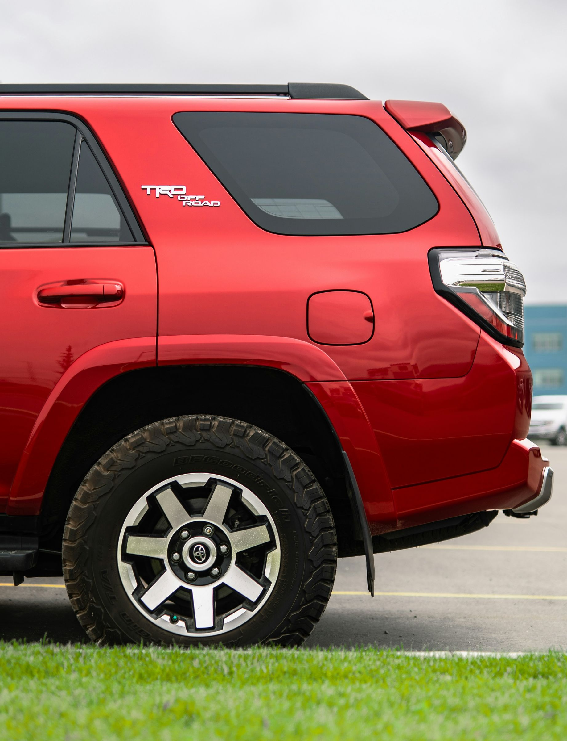 Red Toyota 4Runner TRD Pro SUV parked on grass with a cloudy sky.