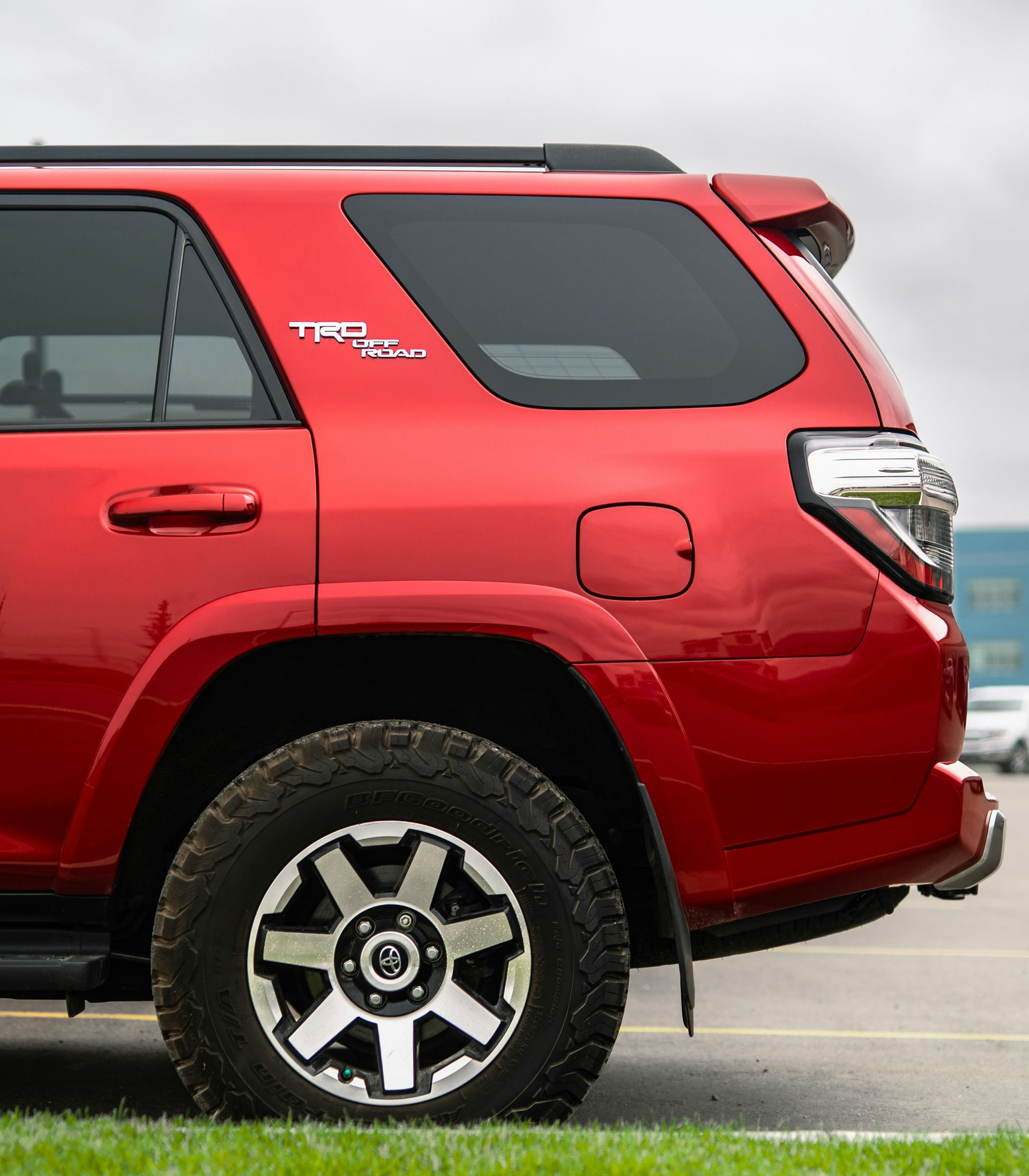 Red Toyota 4Runner TRD Pro SUV parked on grass with a cloudy sky.